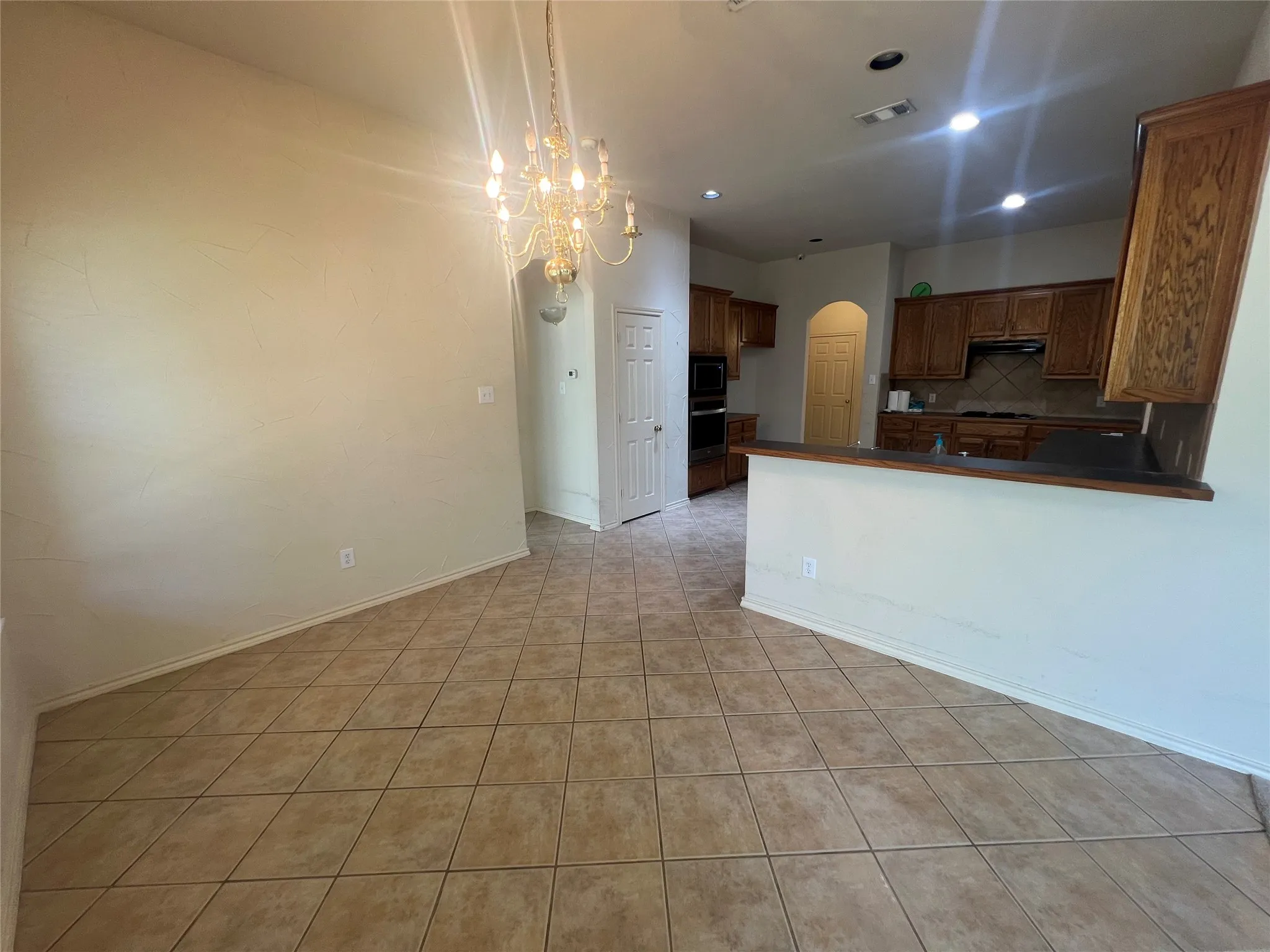 Ceramic tile flooring, kitchen with wood cabinetry, integrated double oven, and recessed lighting