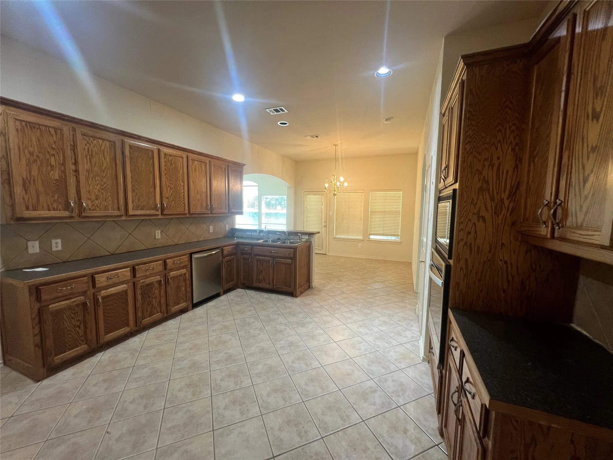 Expansive kitchen featuring wood cabinetry, stainless steel dishwasher, built-in oven, tile flooring, and recessed lighting