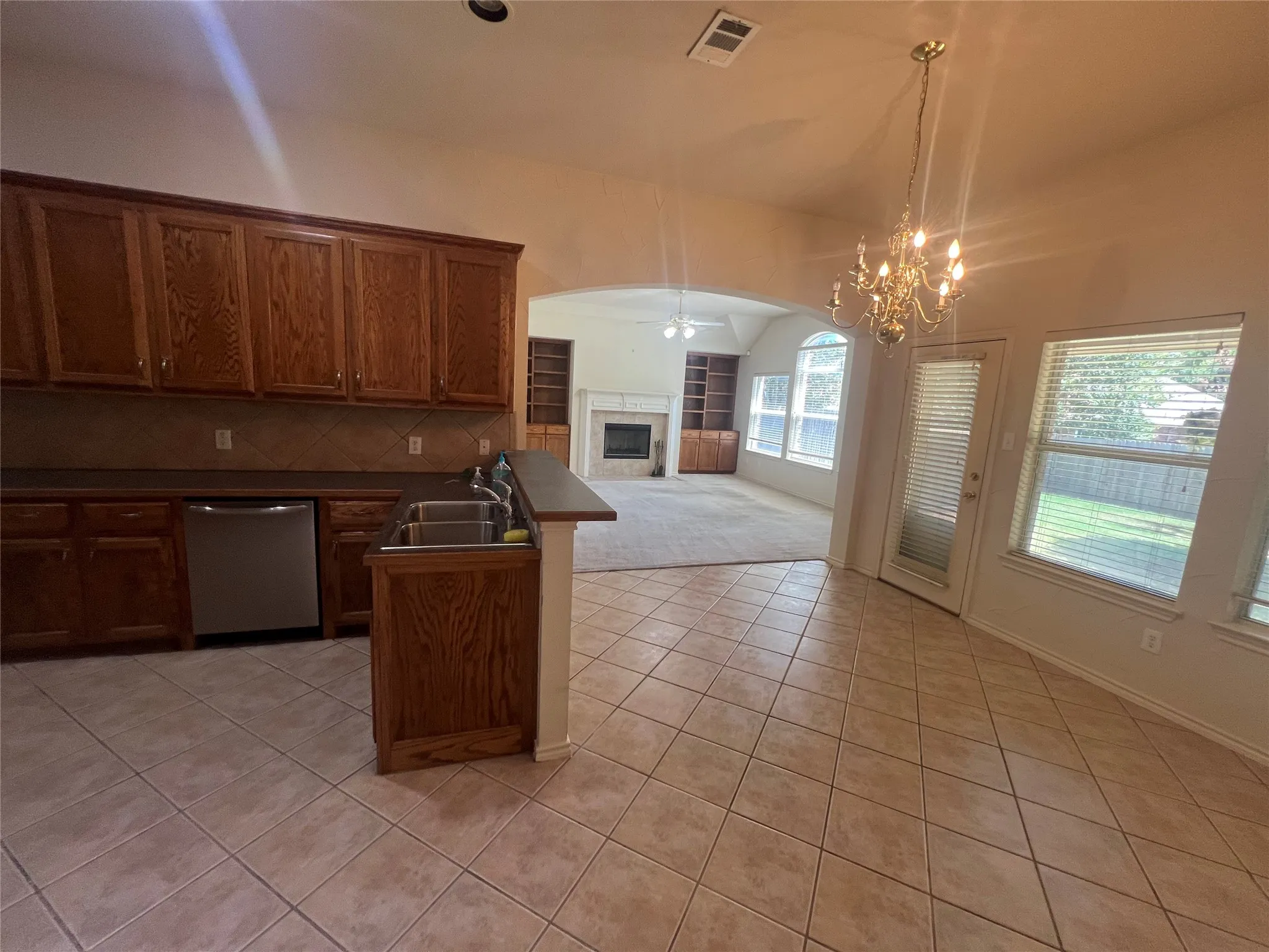 Kitchen featuring wood cabinetry, stainless steel dishwasher, and tile flooring