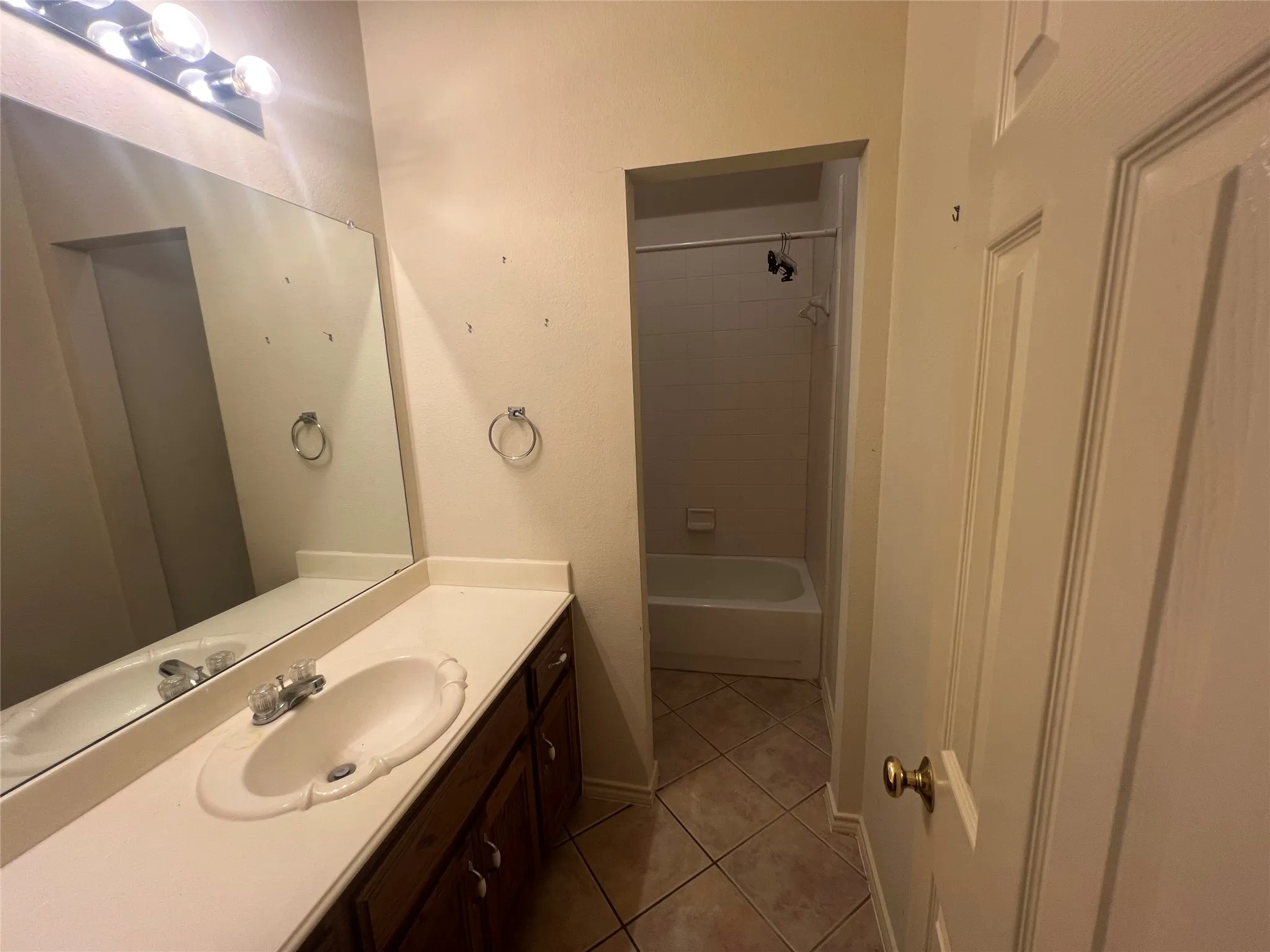 Vanity featuring an integrated sink with a chrome faucet, a large mirror, and a wall-mounted light fixture