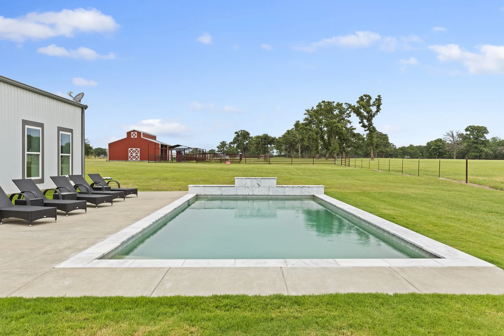 Rectangular swimming pool with white coping and integrated water feature
