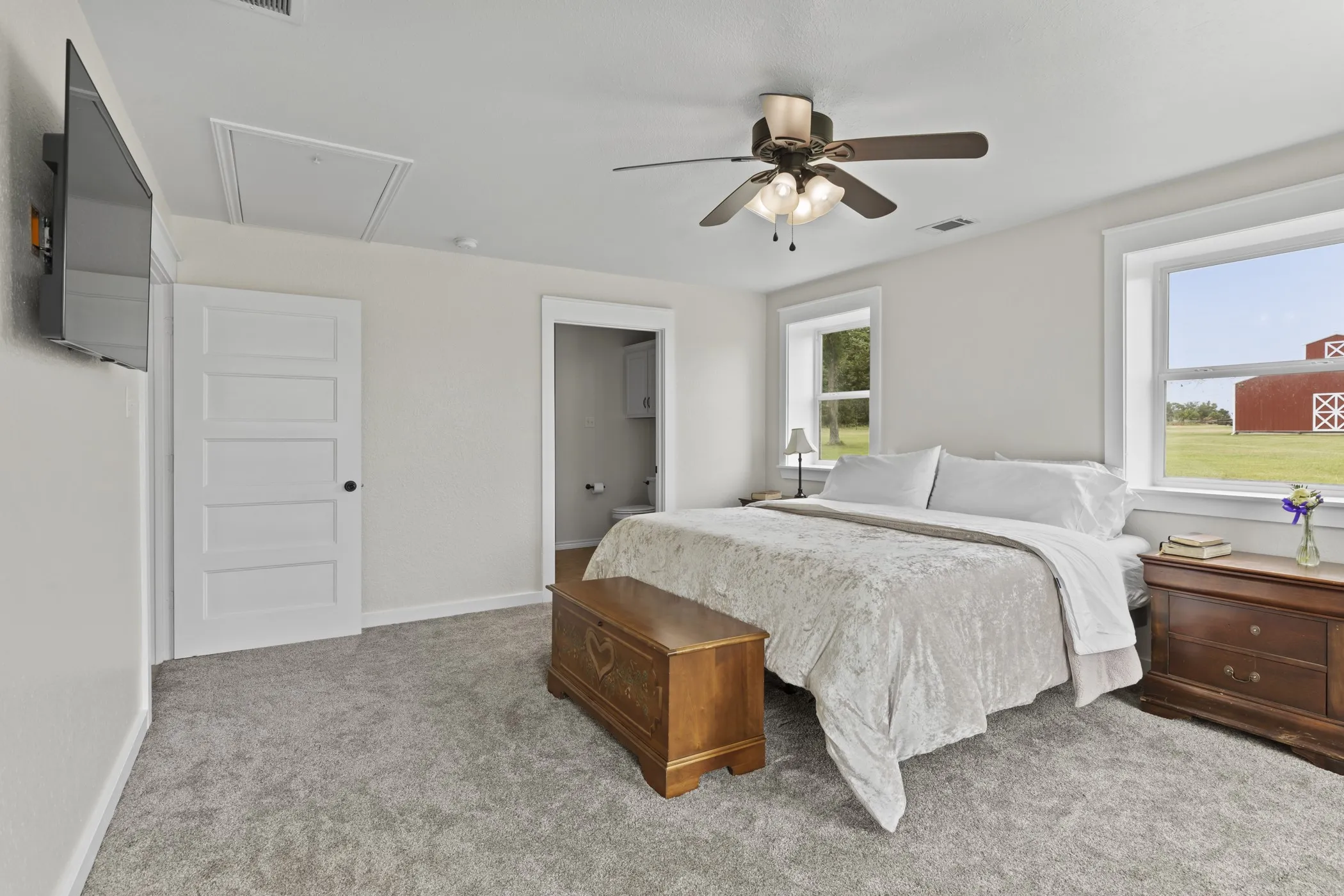 Spacious room featuring light gray carpet flooring, a ceiling fan with integrated lighting, and white trim around windows and doorways