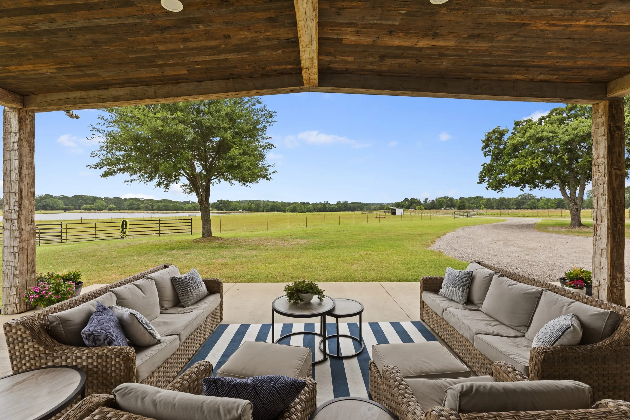 Covered outdoor patio with a plank wood-finish ceiling, stone-clad pillars, and a concrete floor
