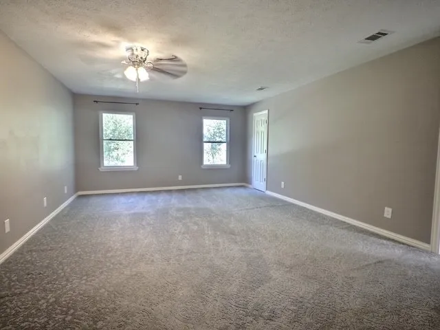 Spacious room featuring neutral-toned walls, patterned carpet, and bright white trim