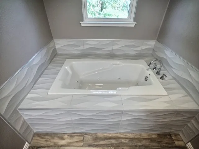 Built-in jetted tub surrounded by textured wave-patterned tiles