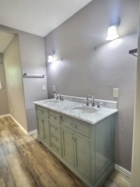 Dual vanity with a light green finish, white marble-style countertop, and integrated sinks