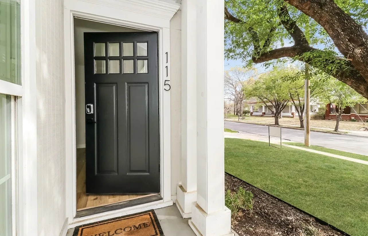 Entryway featuring a black paneled door with windowpanes, contrasting white trim, and visible house numbers