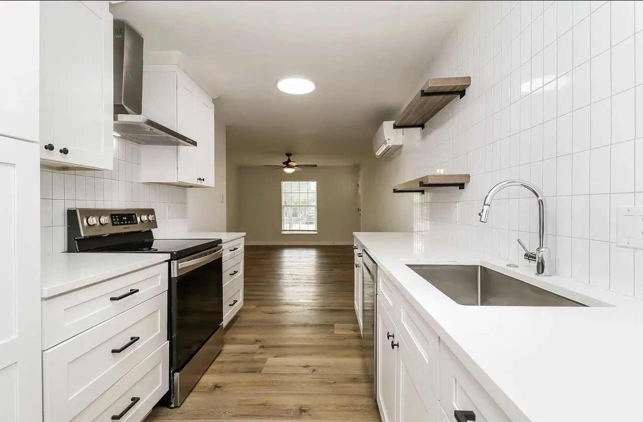 Modern kitchen featuring white shaker cabinetry, stainless steel appliances, solid surface countertops, a subway tile backsplash, and wood-finish flooring