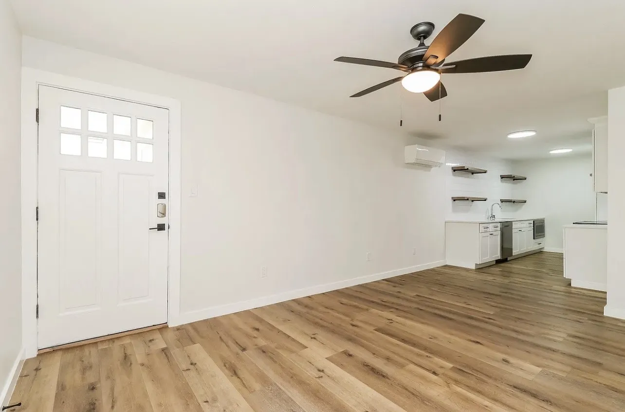 Bright interior space featuring wood-finish flooring, a contemporary ceiling fan, and a paneled entry door with frosted glass inserts