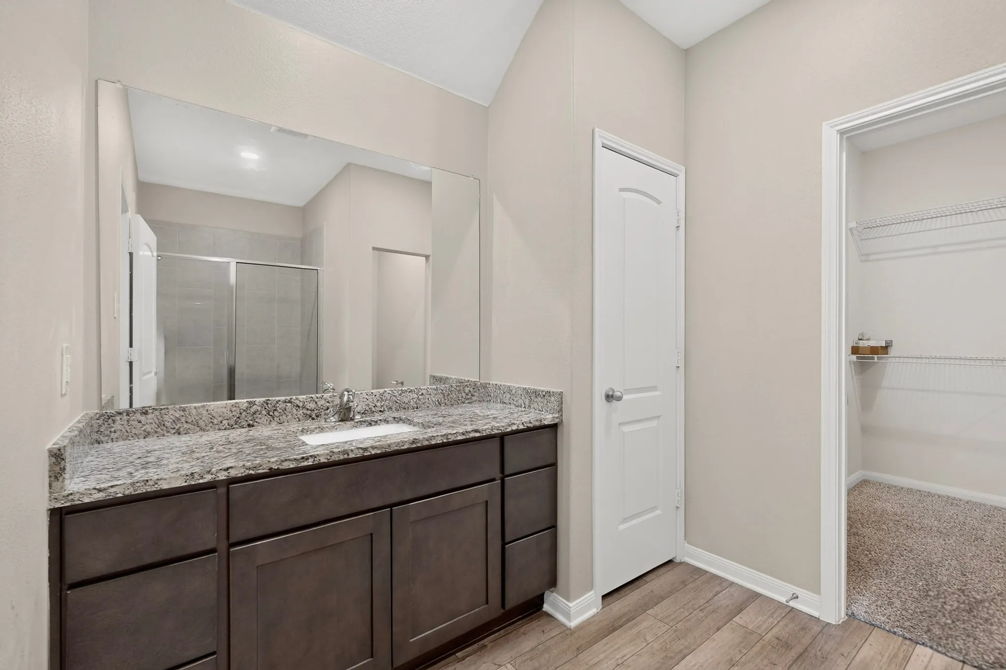 Bathroom vanity featuring a granite countertop with an undermount sink, dark wood-finish cabinetry, and a full-width mirror