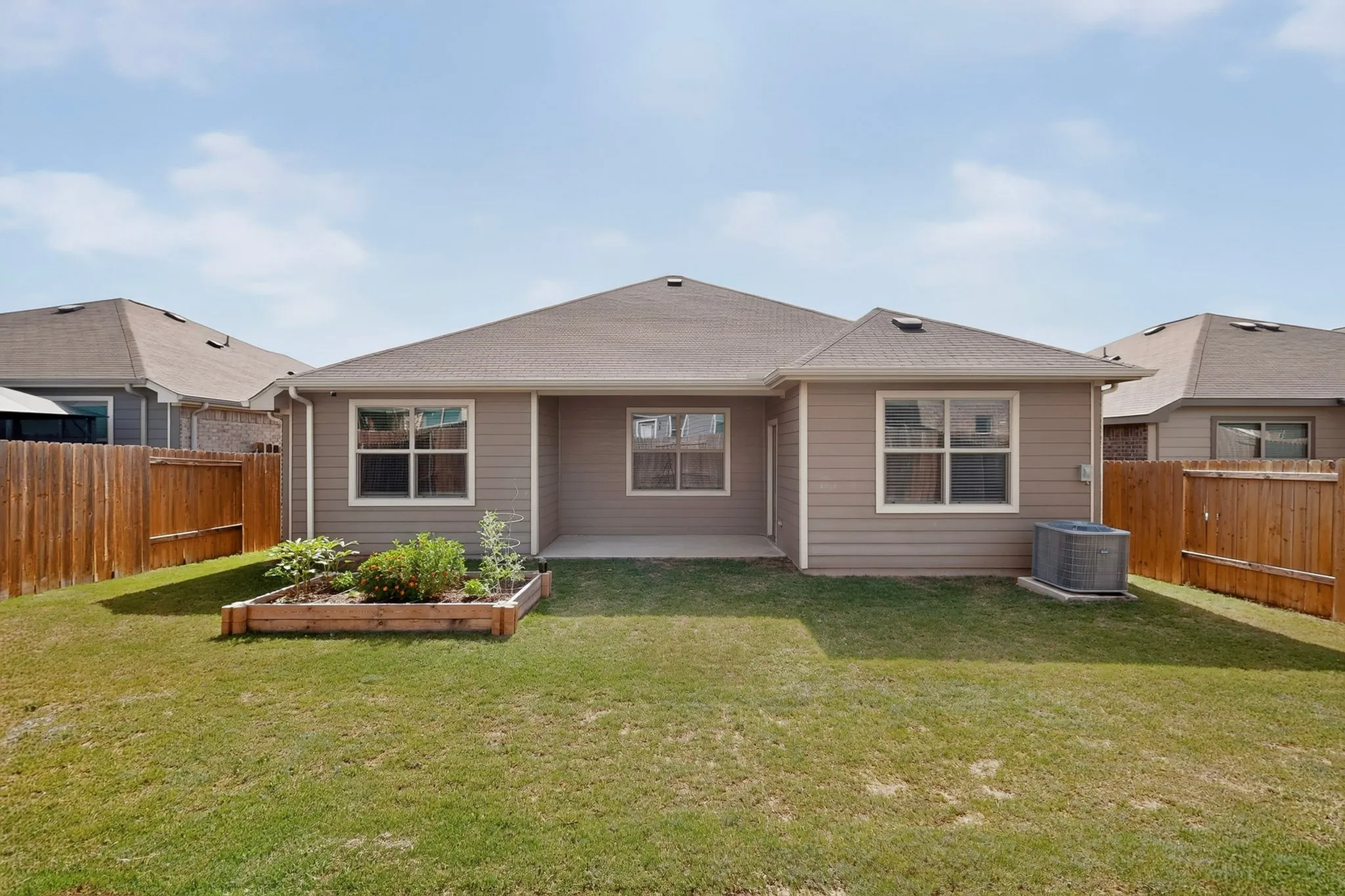 Expansive rear yard featuring a lawn, privacy fencing, and a raised garden bed