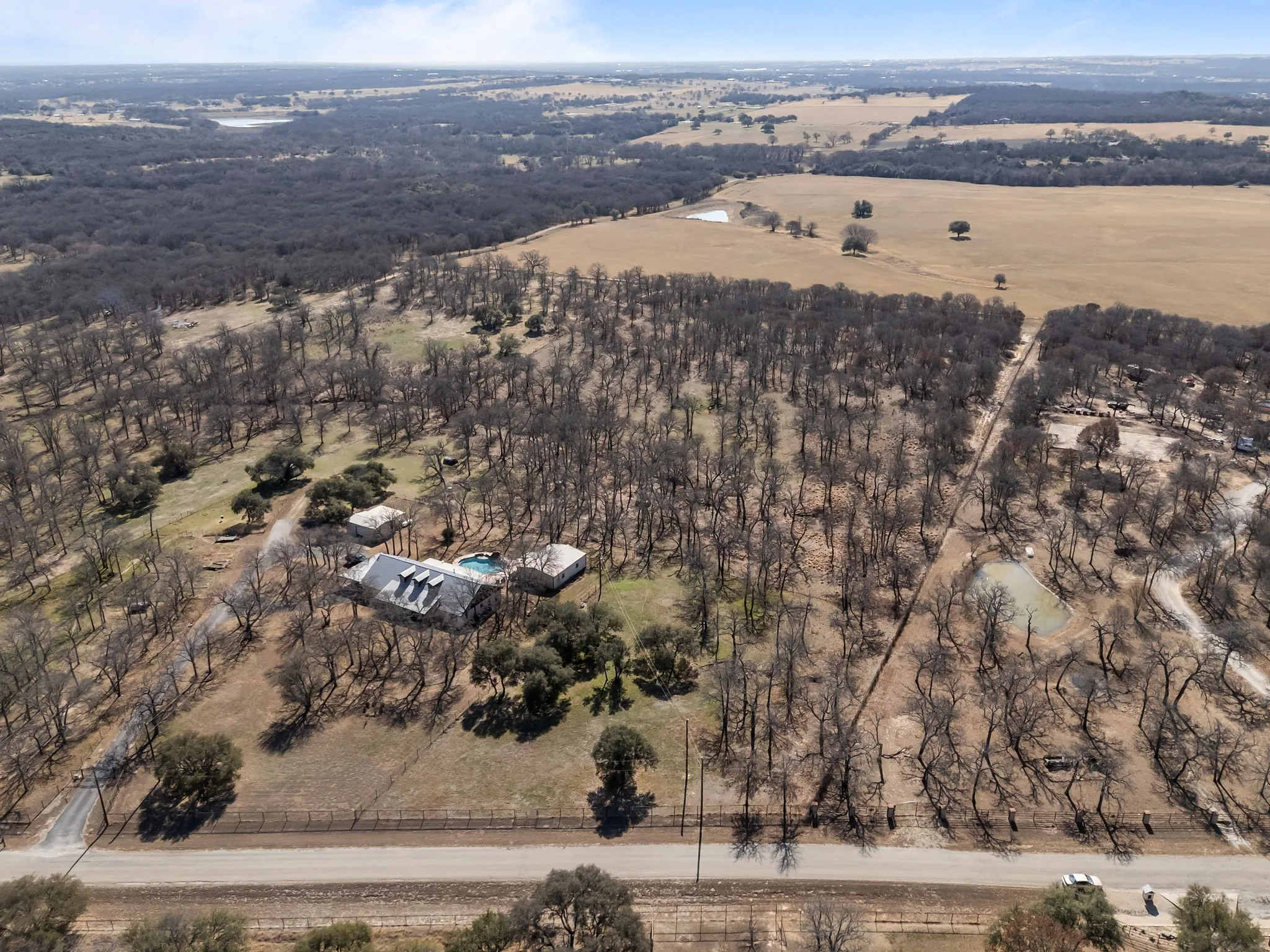 Expansive rural property featuring a main residence with a swimming pool, multiple outbuildings, and extensive wooded areas