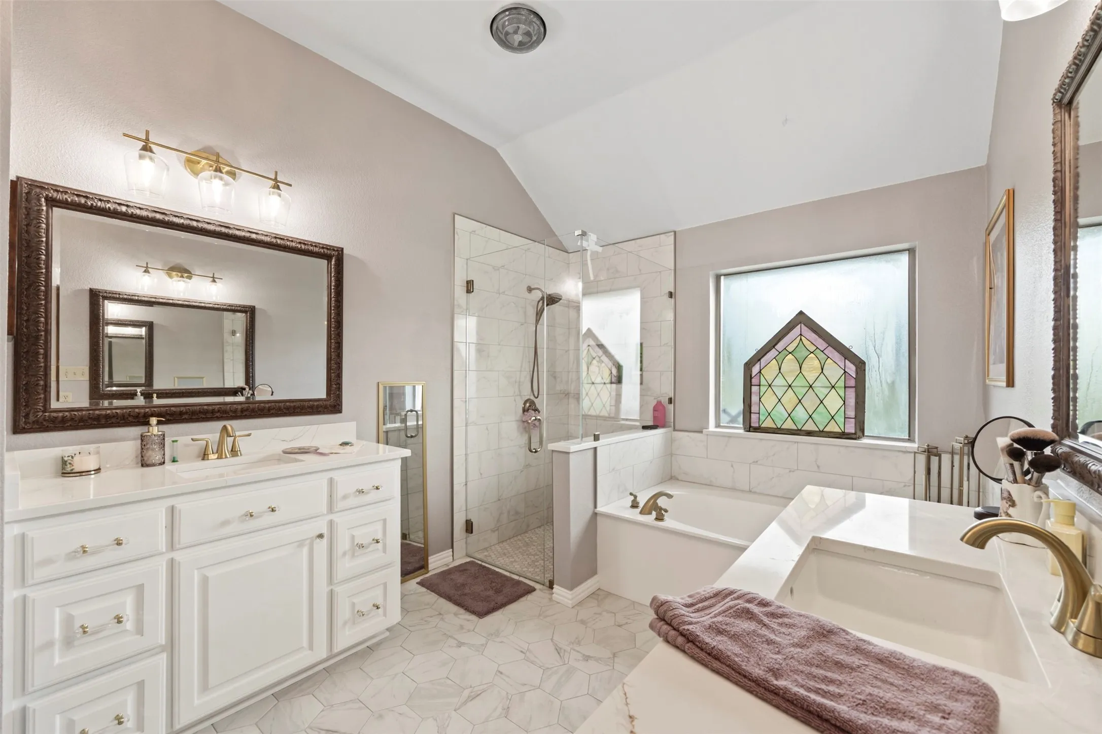 Lovely primary bathroom with separate vanities and decorative fixtures.