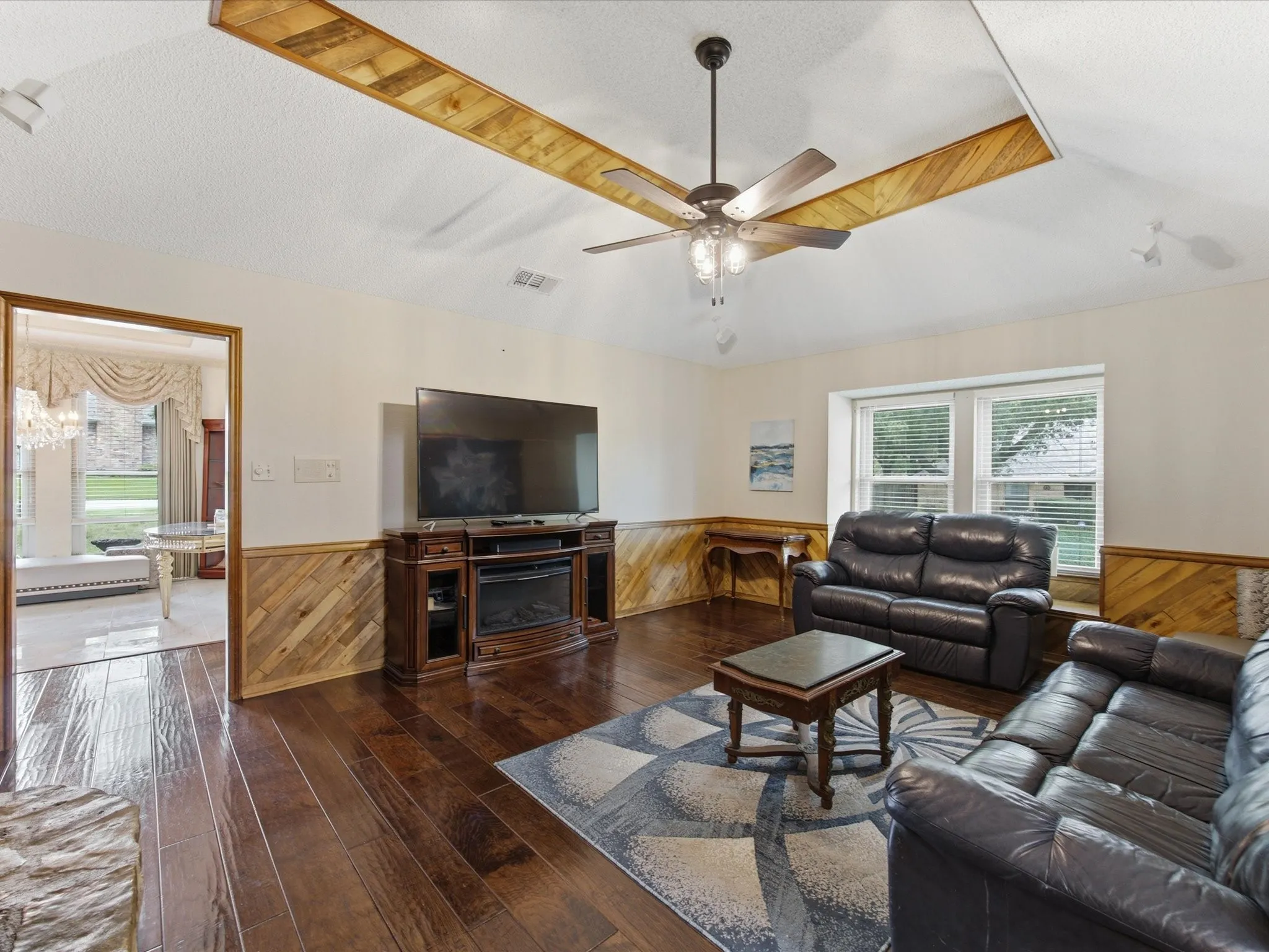 Living area featuring wood-finish flooring, wood paneling, and a vaulted ceiling with decorative wood accents