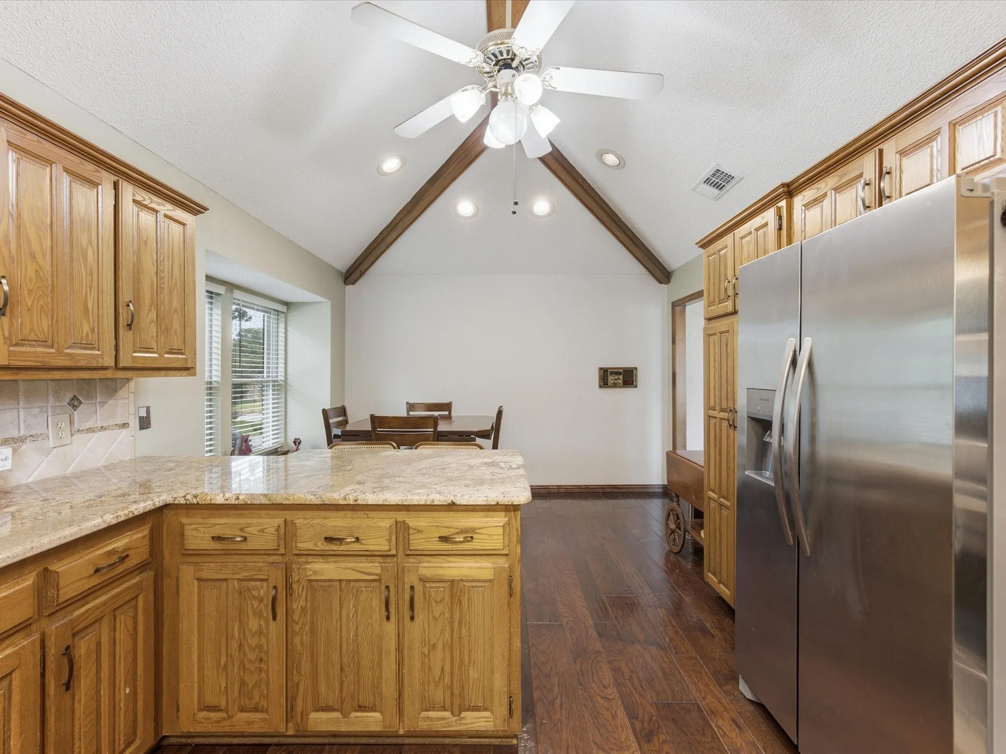 Kitchen featuring wood-finish cabinetry, light granite countertops, and a tiled backsplash