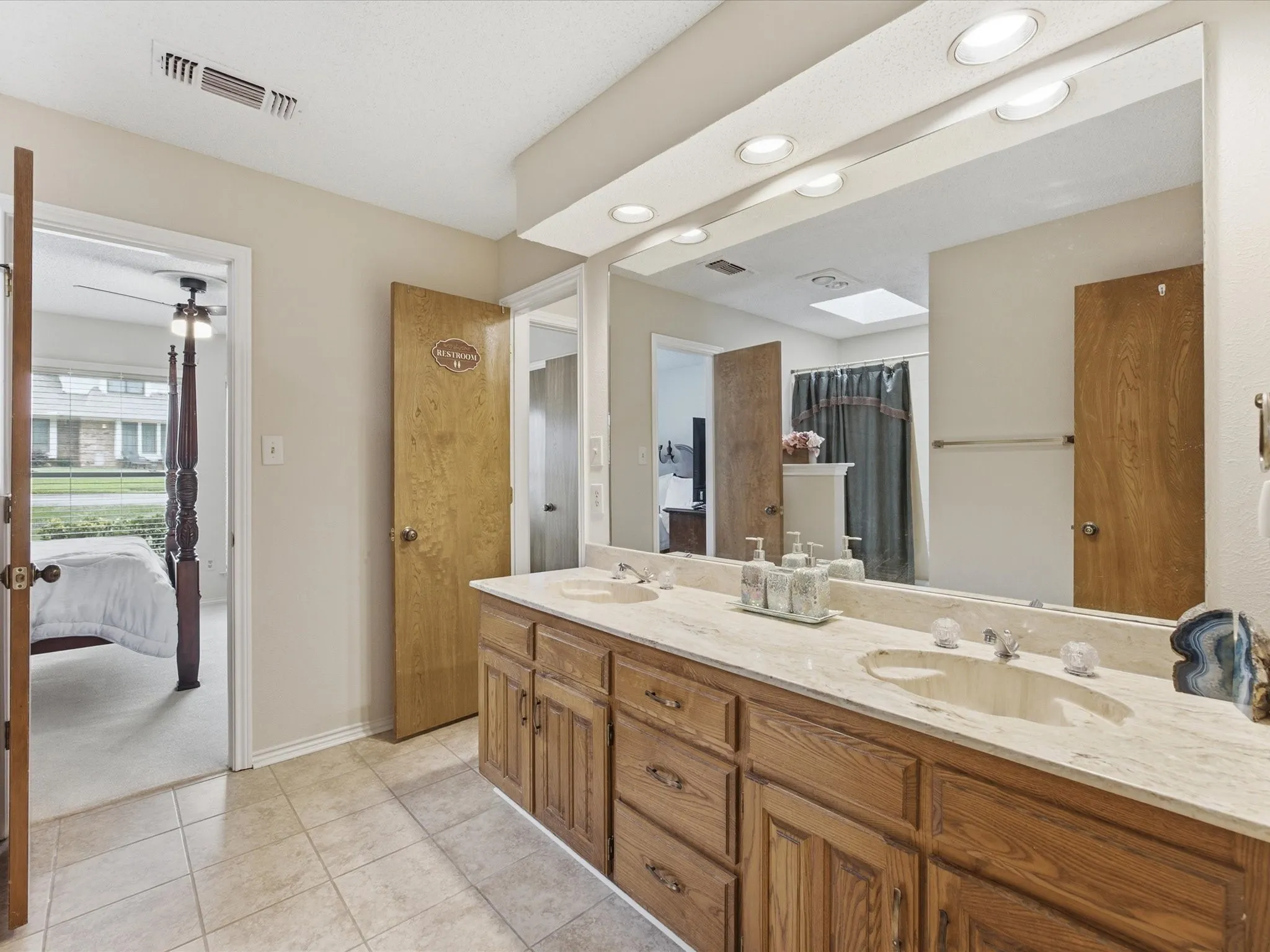 Dual vanity with integrated sinks, light-toned countertop, and wood-finish cabinetry