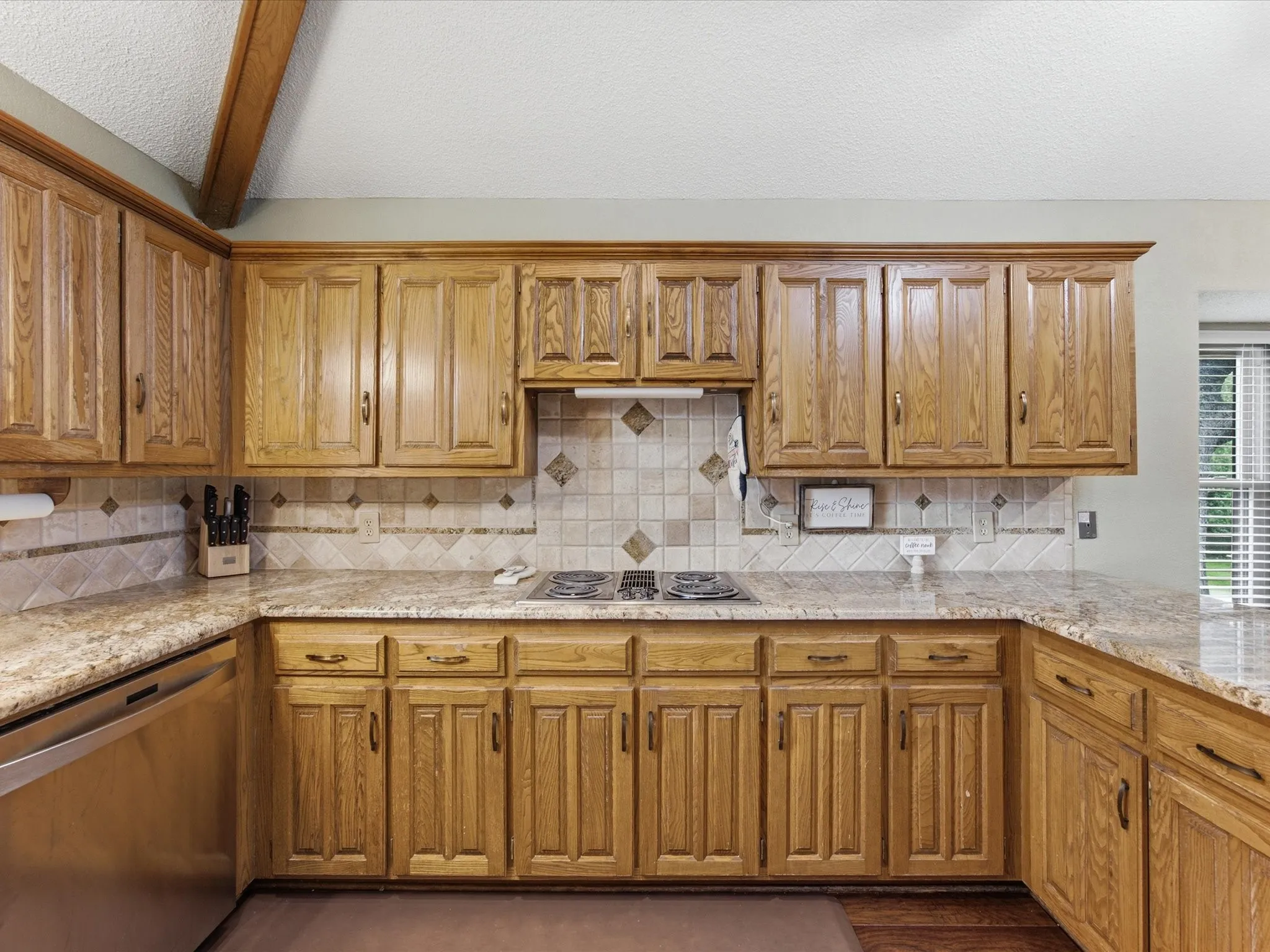 Kitchen featuring wood cabinetry, granite-style countertops, and a tiled backsplash