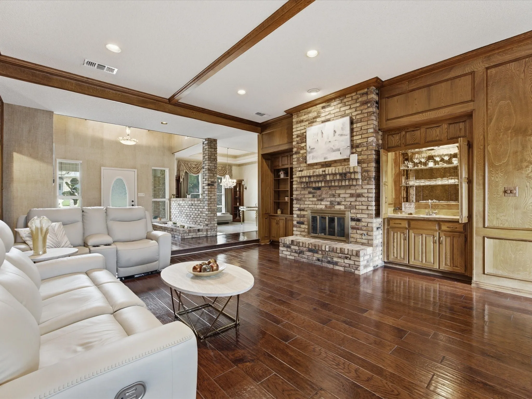 Open-concept living space featuring wood-finish flooring, a brick fireplace, and extensive wood paneling