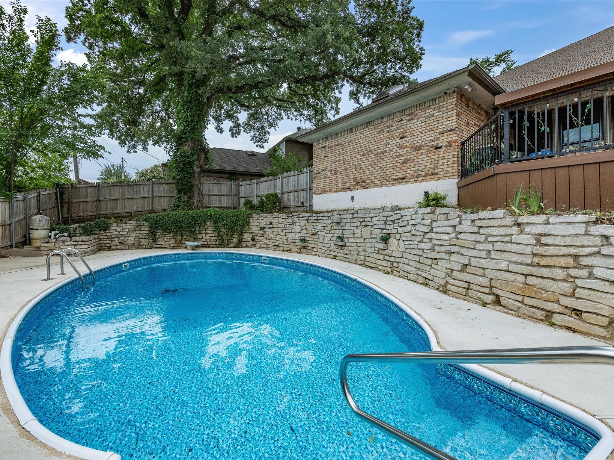 Oval-shaped swimming pool featuring a bright blue liner and concrete decking