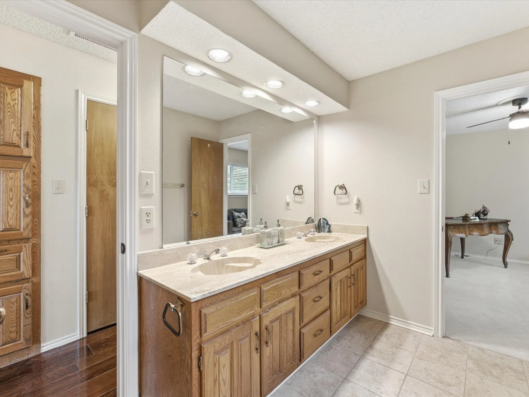 Dual vanity with light wood cabinetry, a light-toned countertop, and undermount sinks
