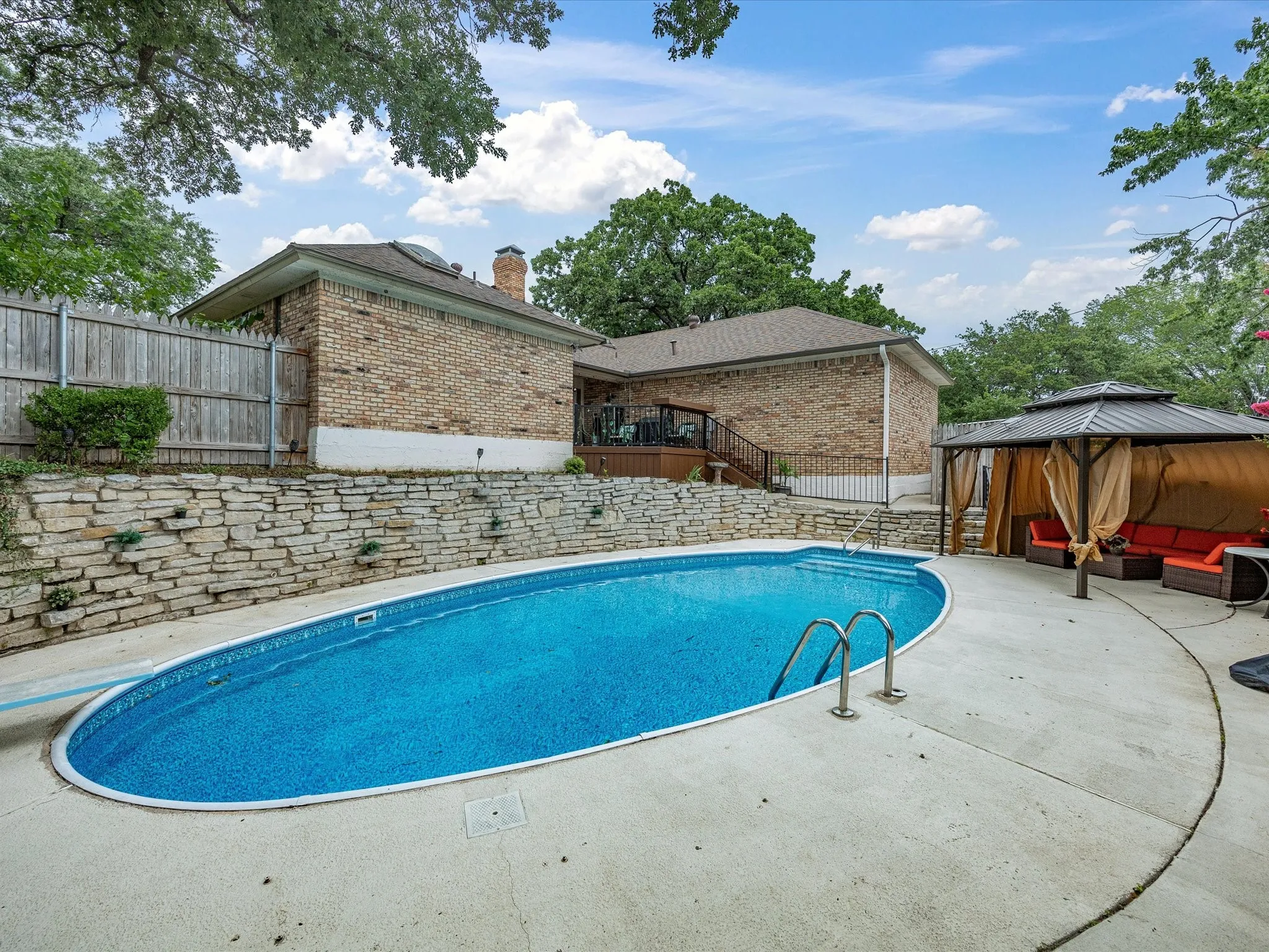 Oval swimming pool with integrated steps, surrounded by a concrete patio