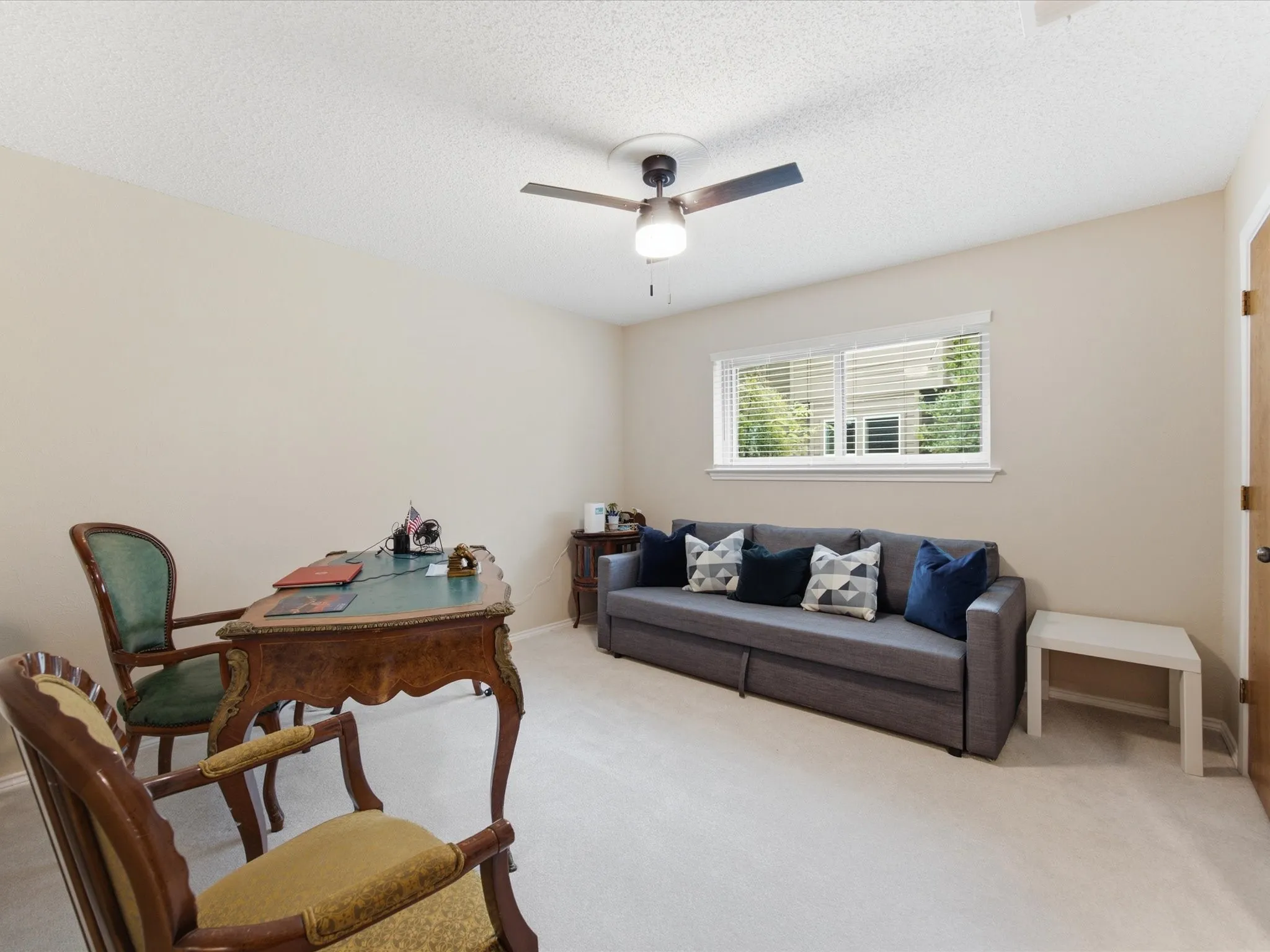Spacious room featuring neutral carpeting, a ceiling fan, and a window with blinds