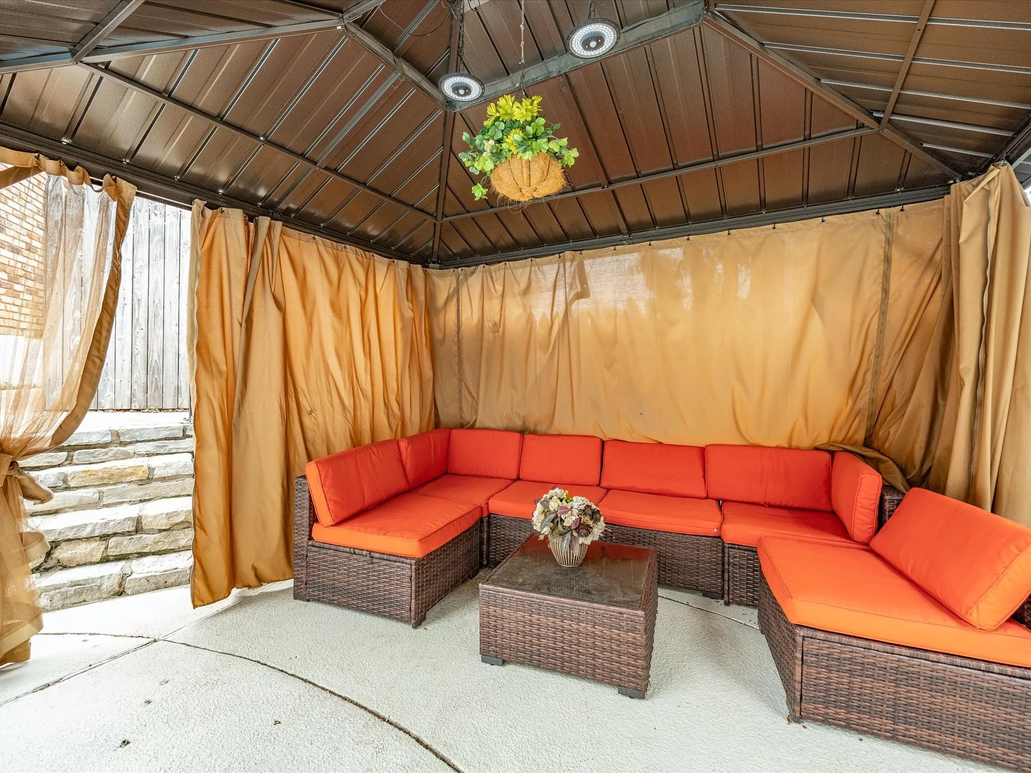 Outdoor gazebo featuring a metal roof structure, privacy curtains, and a concrete patio surface