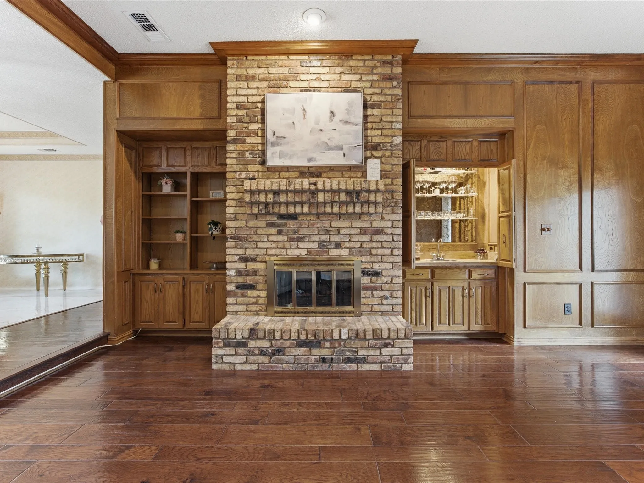 Brick fireplace with wood mantle, flanked by built-in wood cabinetry and shelving