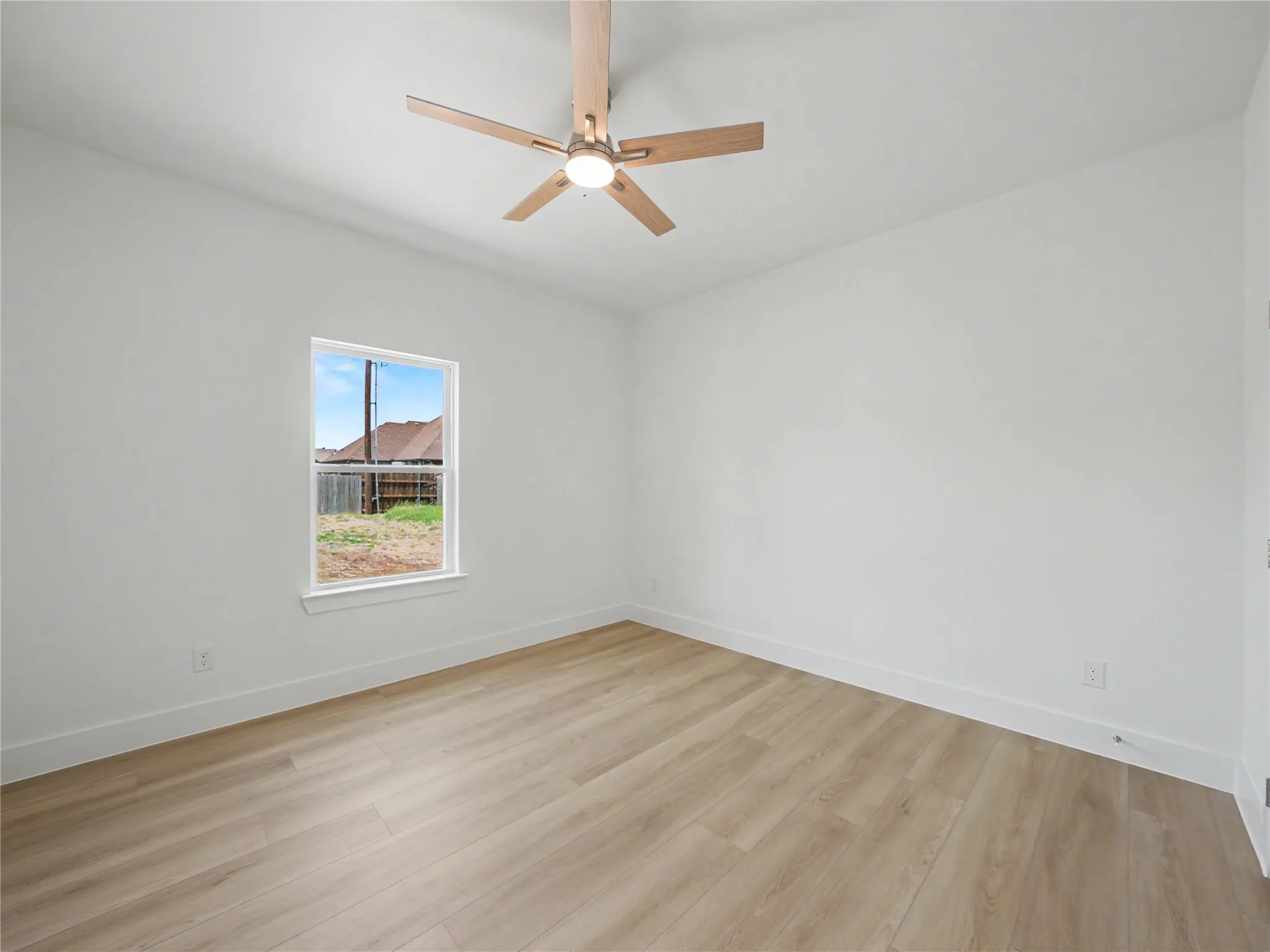 Neutral white walls featuring a single window and light wood-finish flooring