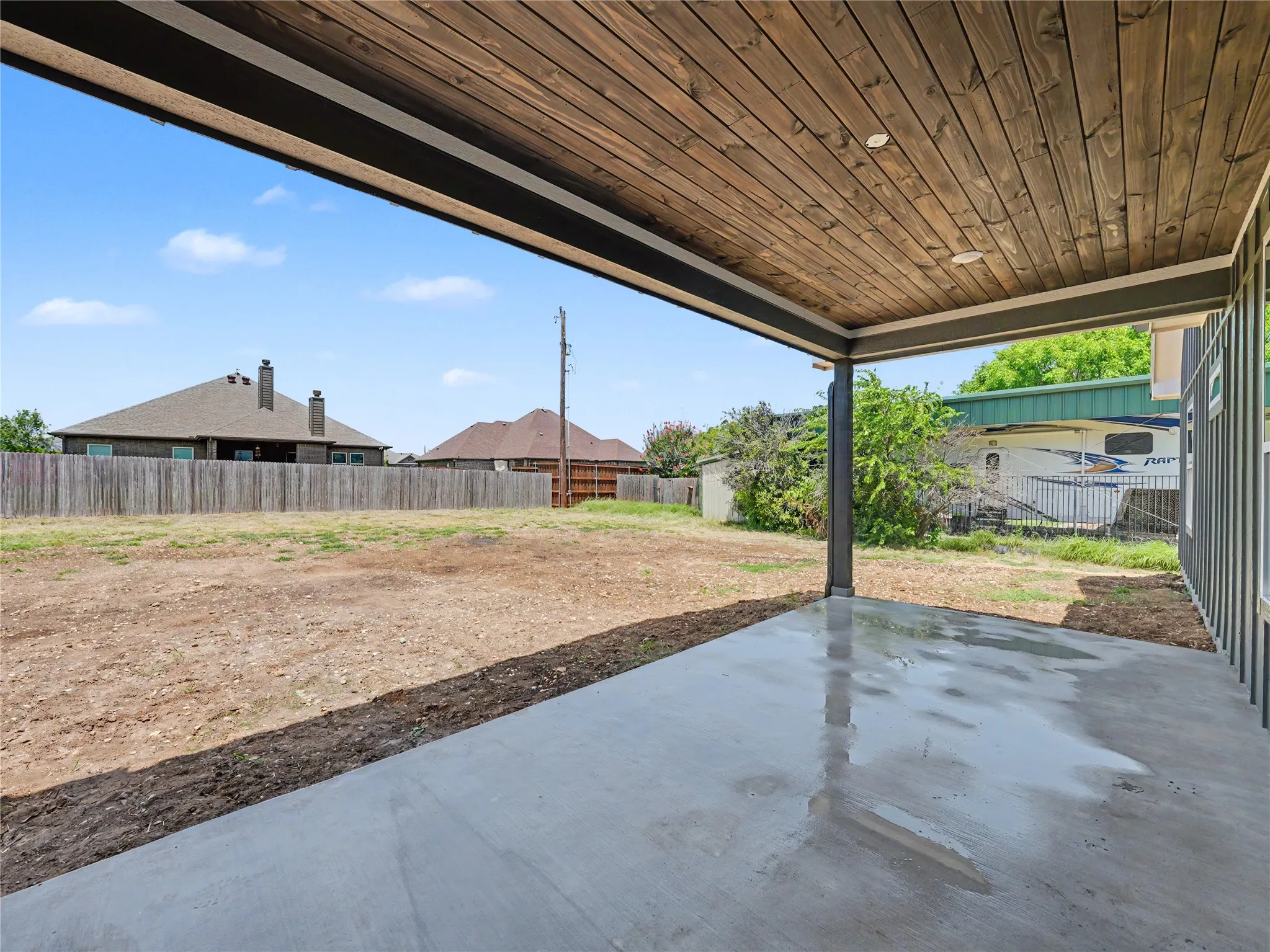 Covered concrete patio with a wood-finish ceiling, recessed lighting, and a metal support column