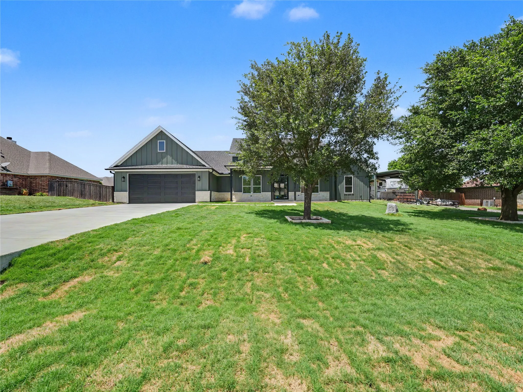 Contemporary home with a dark green exterior, board and batten siding, and an attached two-car garage