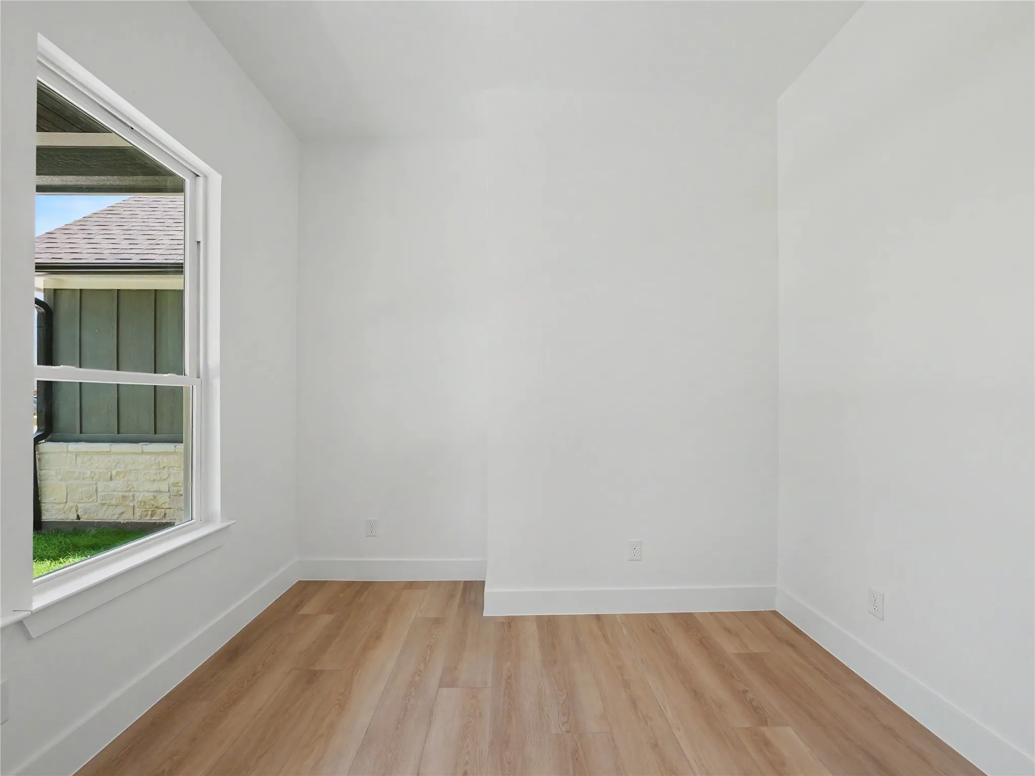 Room featuring white walls, wood-finish flooring, and white baseboards
