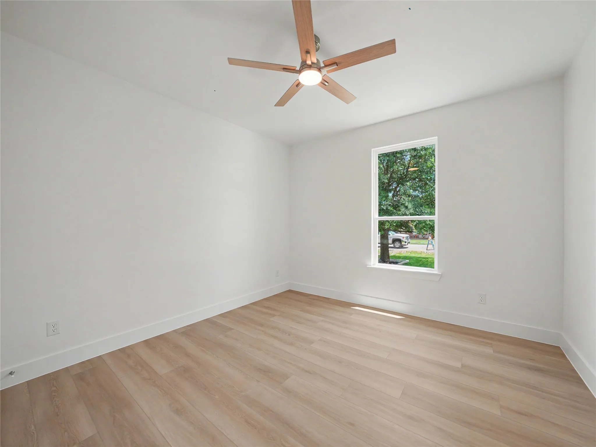 Bedroom featuring wood-finish flooring, white walls, and a contemporary ceiling fan with integrated lighting