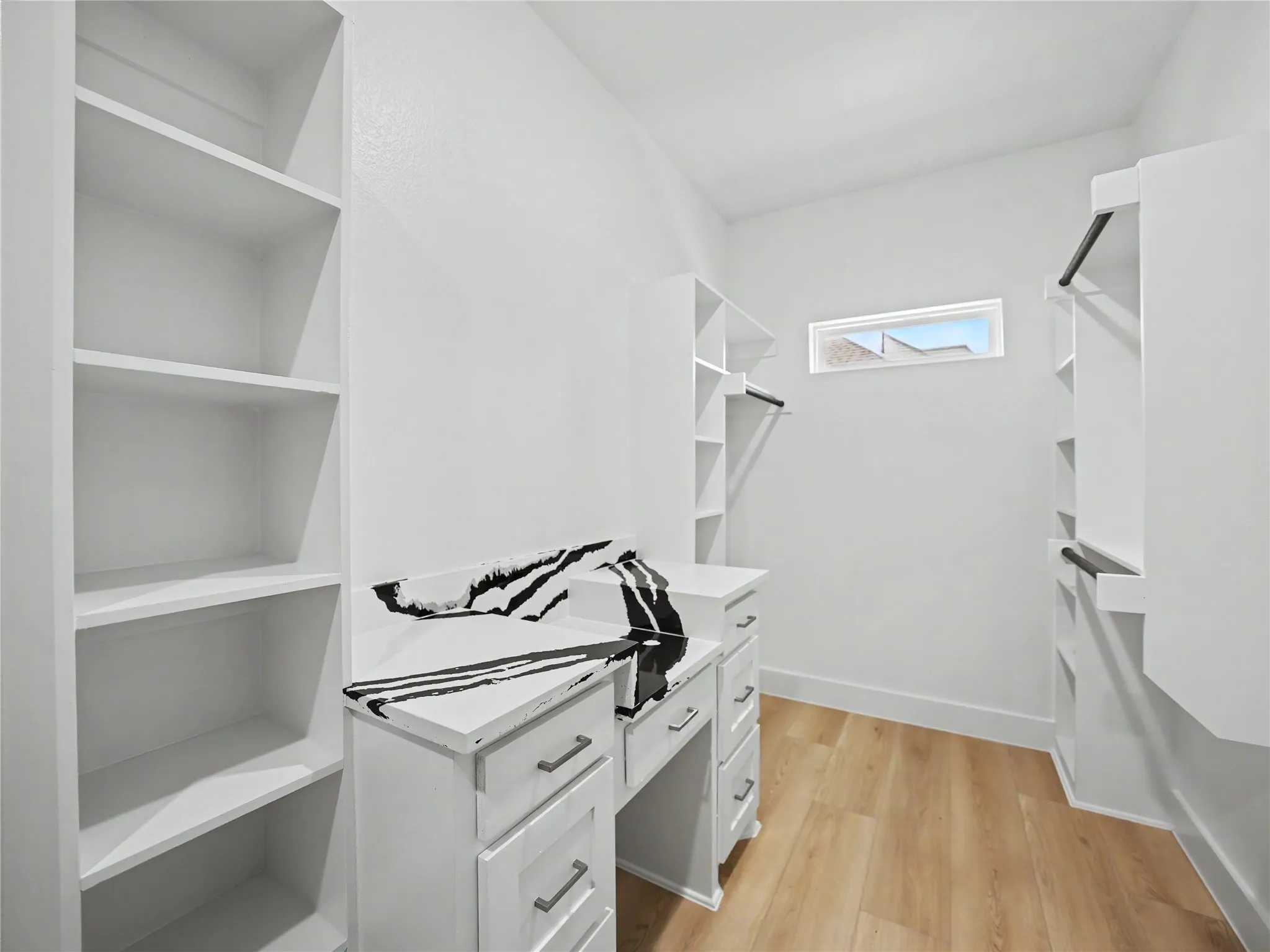 Walk-in closet featuring extensive built-in shelving, hanging rods, and wood-finish flooring