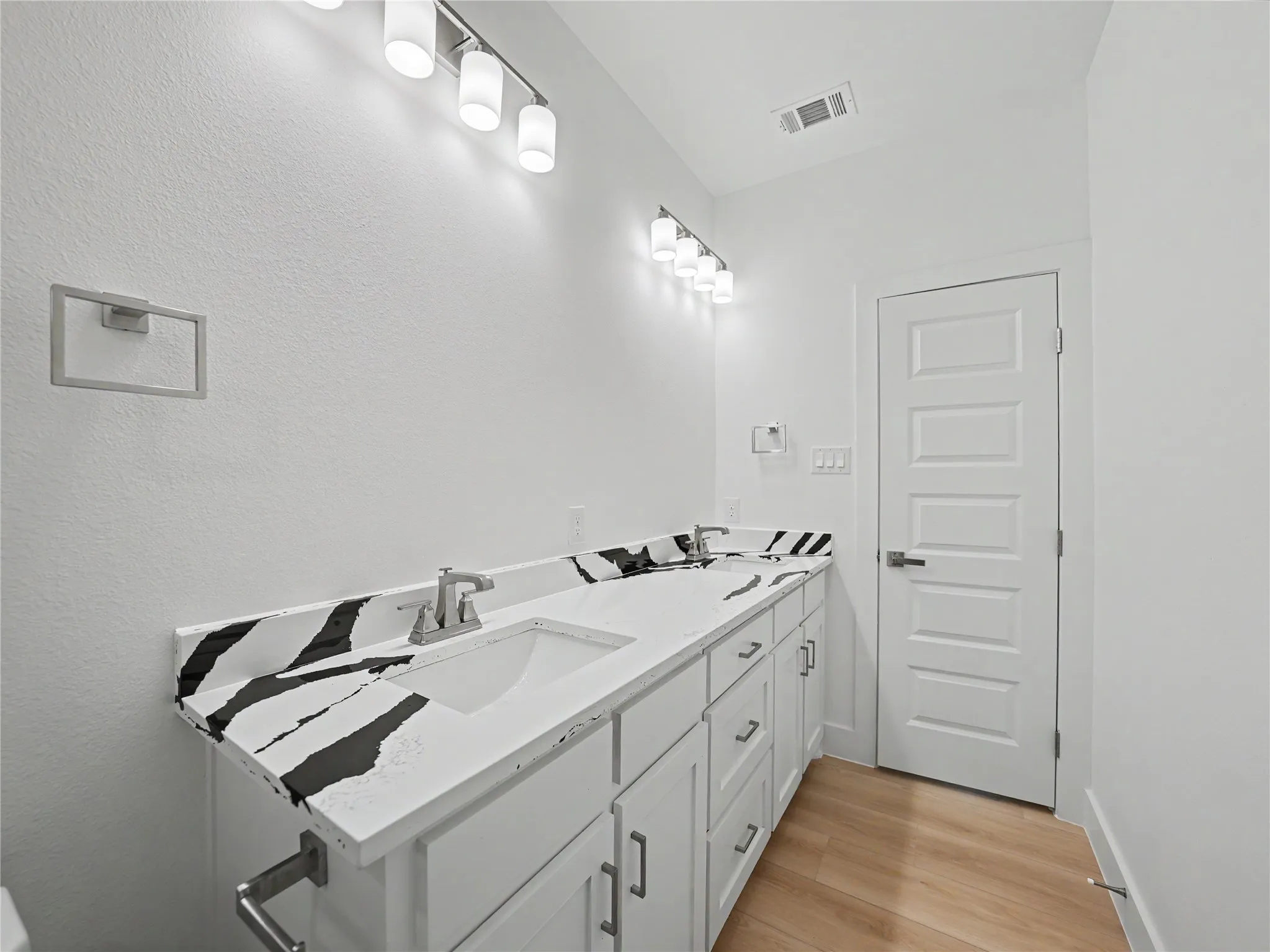 Double vanity with modern white cabinetry and contrasting black and white patterned countertops