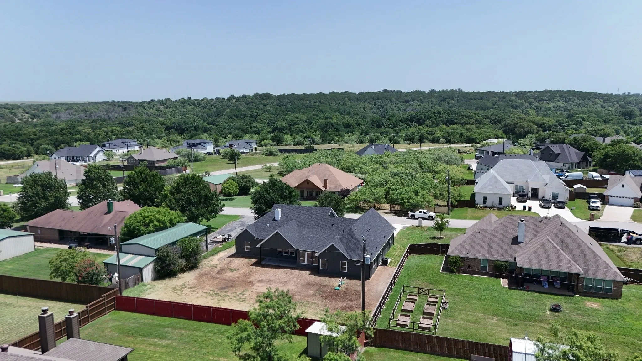 Aerial perspective showcasing a residential area with a prominent backdrop of dense green trees