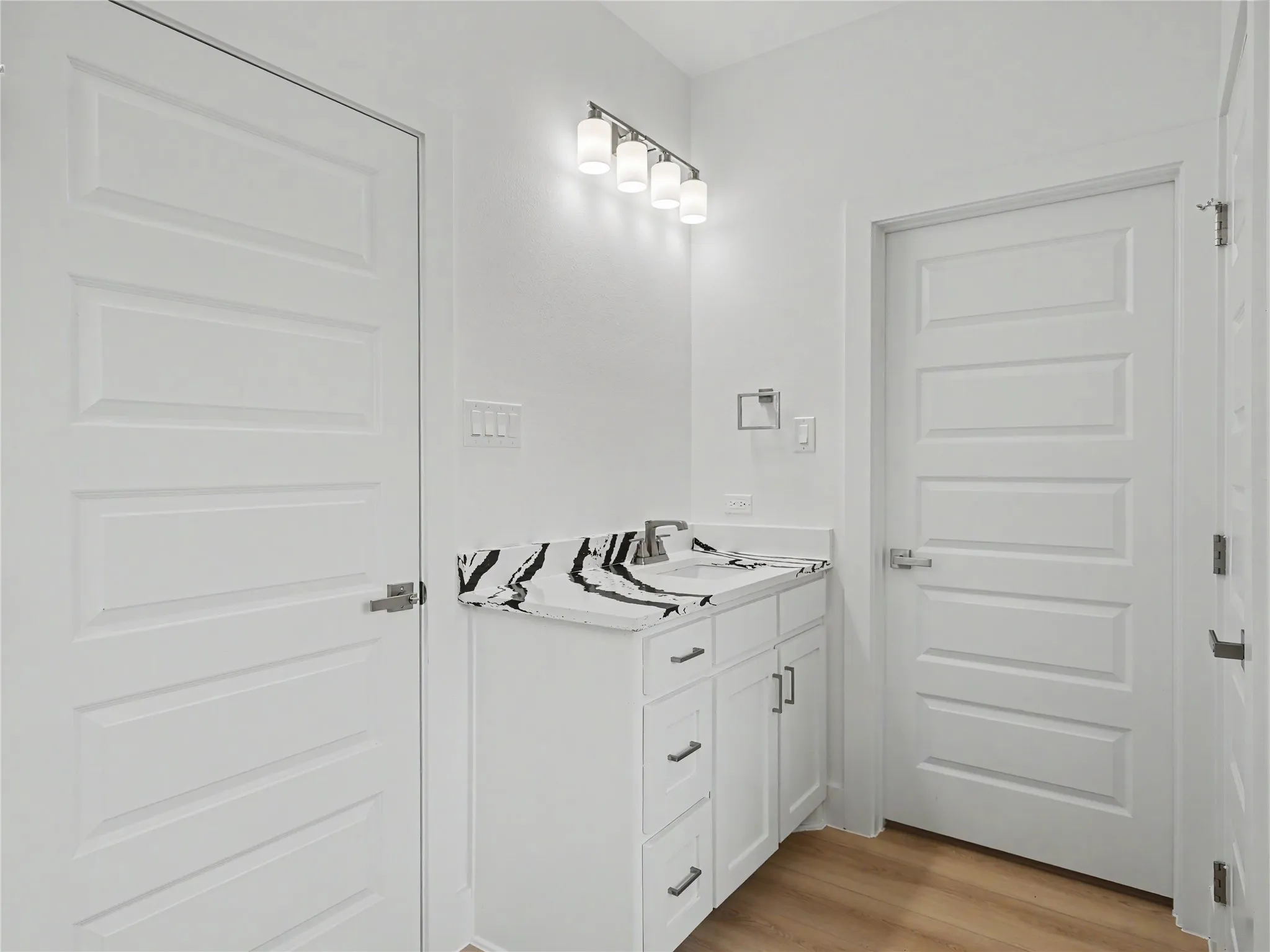 Bathroom vanity featuring a white cabinet, integrated sink, and patterned countertop