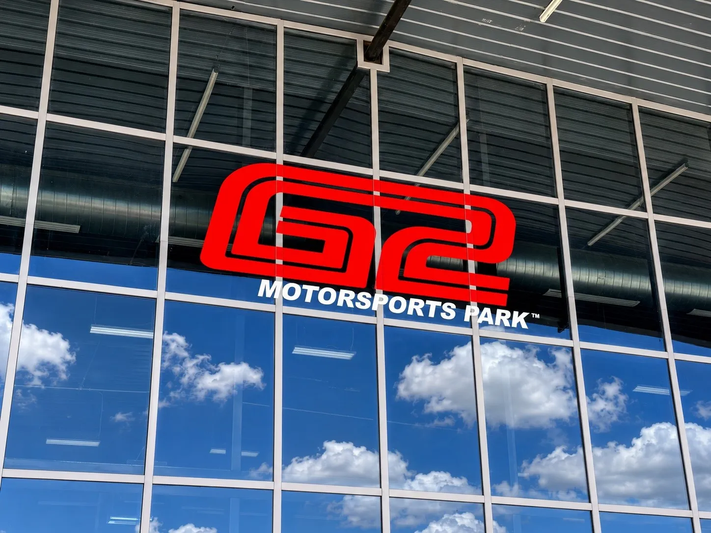 Modern glass storefront featuring a red "G2 MOTORSPORTS PARK" logo