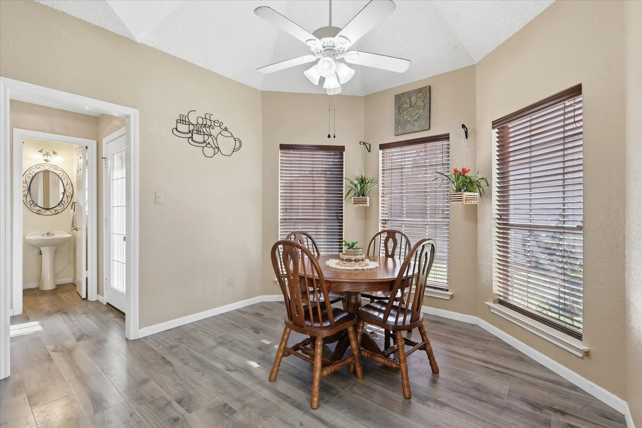 Dining area featuring wood-finish flooring, a vaulted ceiling, and a ceiling fan