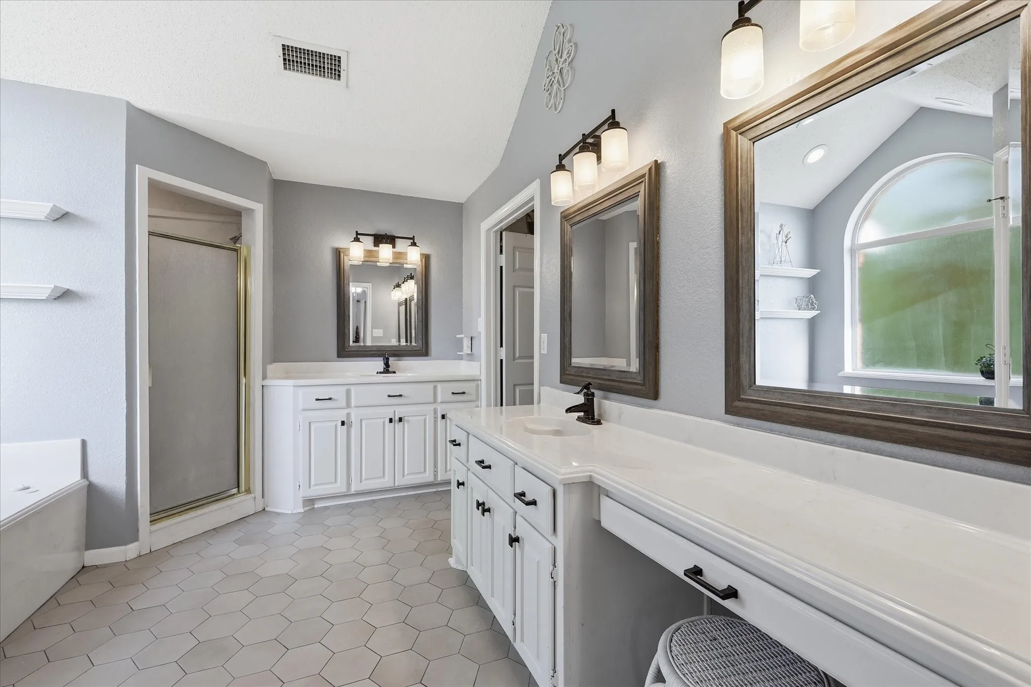 Dual vanity with white cabinetry, solid surface countertops, and framed mirrors
