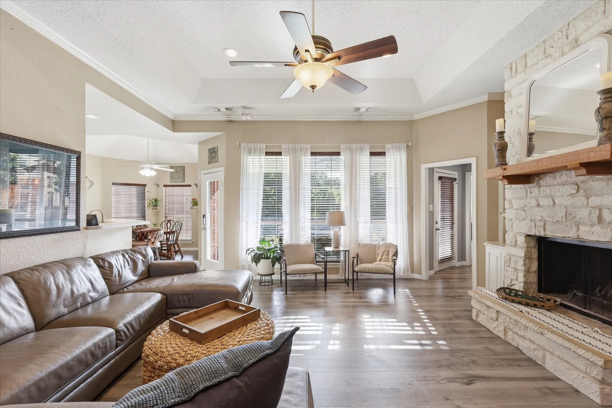 Living area with wood-finish flooring, a tray ceiling, and a ceiling fan
