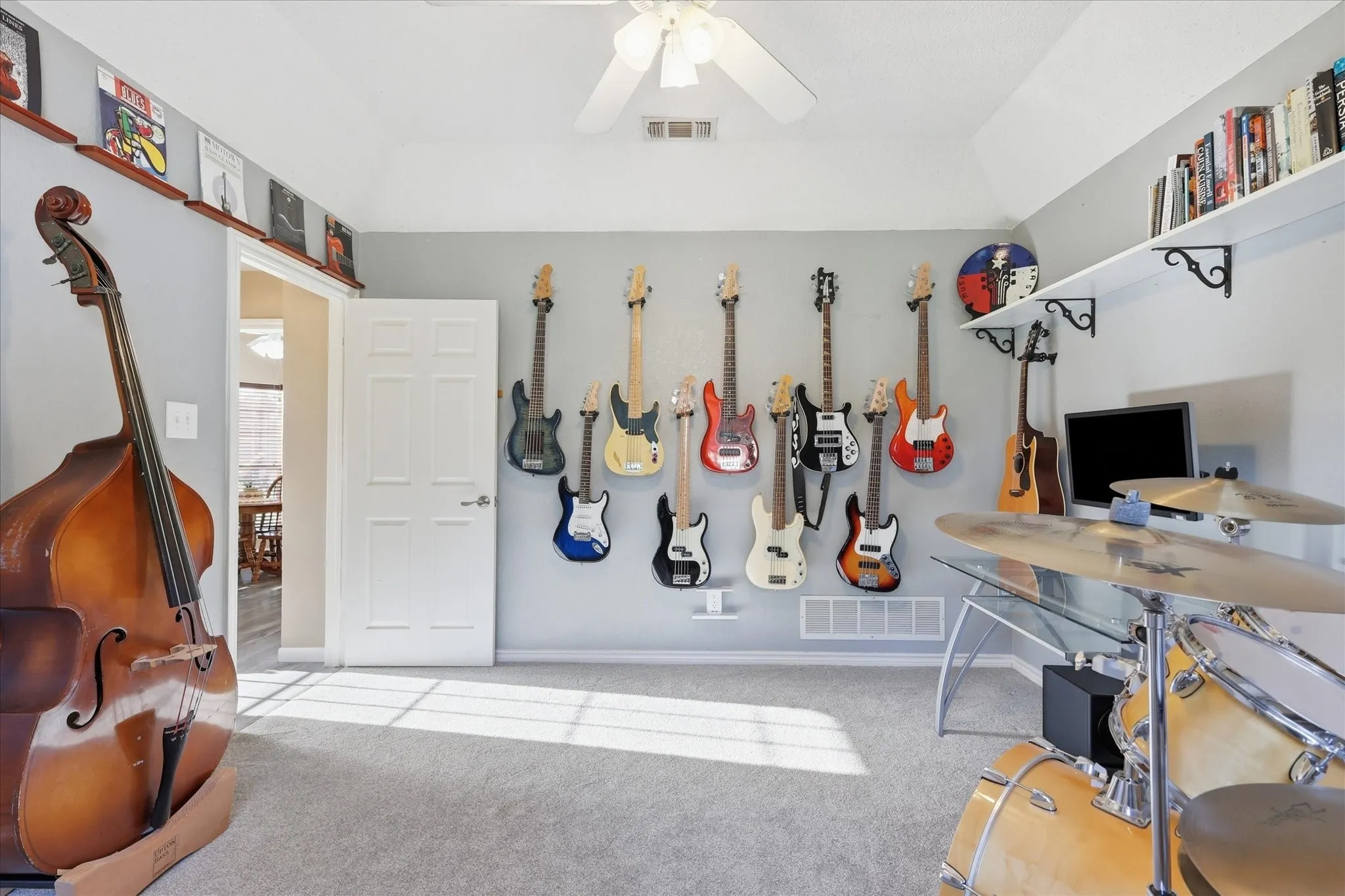 Carpeted room featuring a vaulted ceiling with a fan, a paneled door, and built-in floating shelves