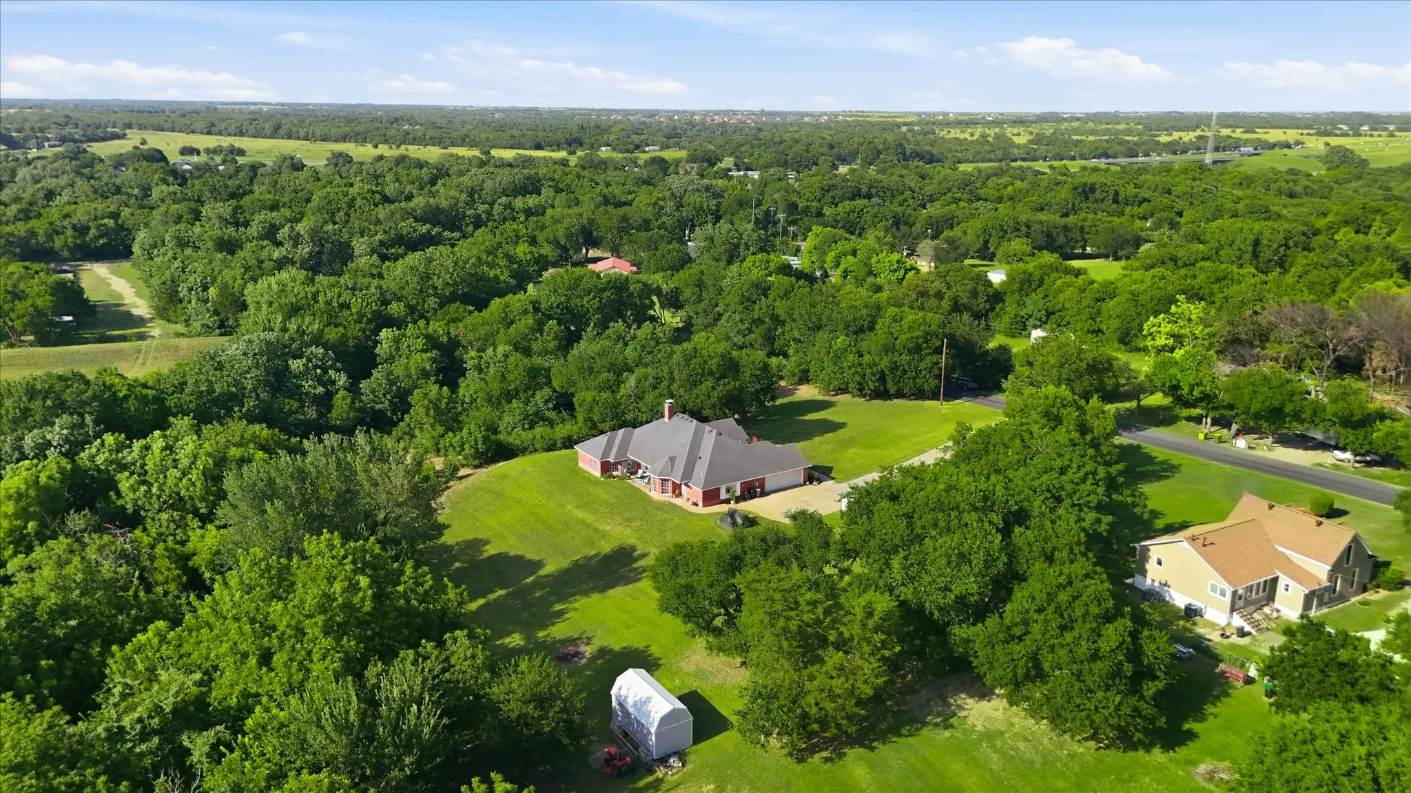 Expansive acreage featuring a brick-clad home with a gabled roofline and chimney