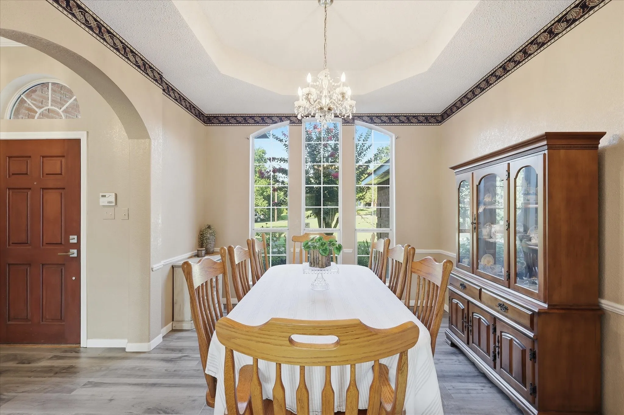 Formal dining area with large bay windows, a tray ceiling, and a crystal chandelier