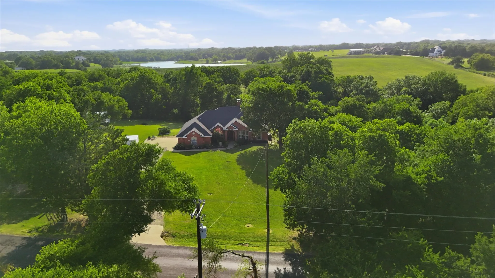 Aerial perspective showcasing a single-story brick residence with a dark roof