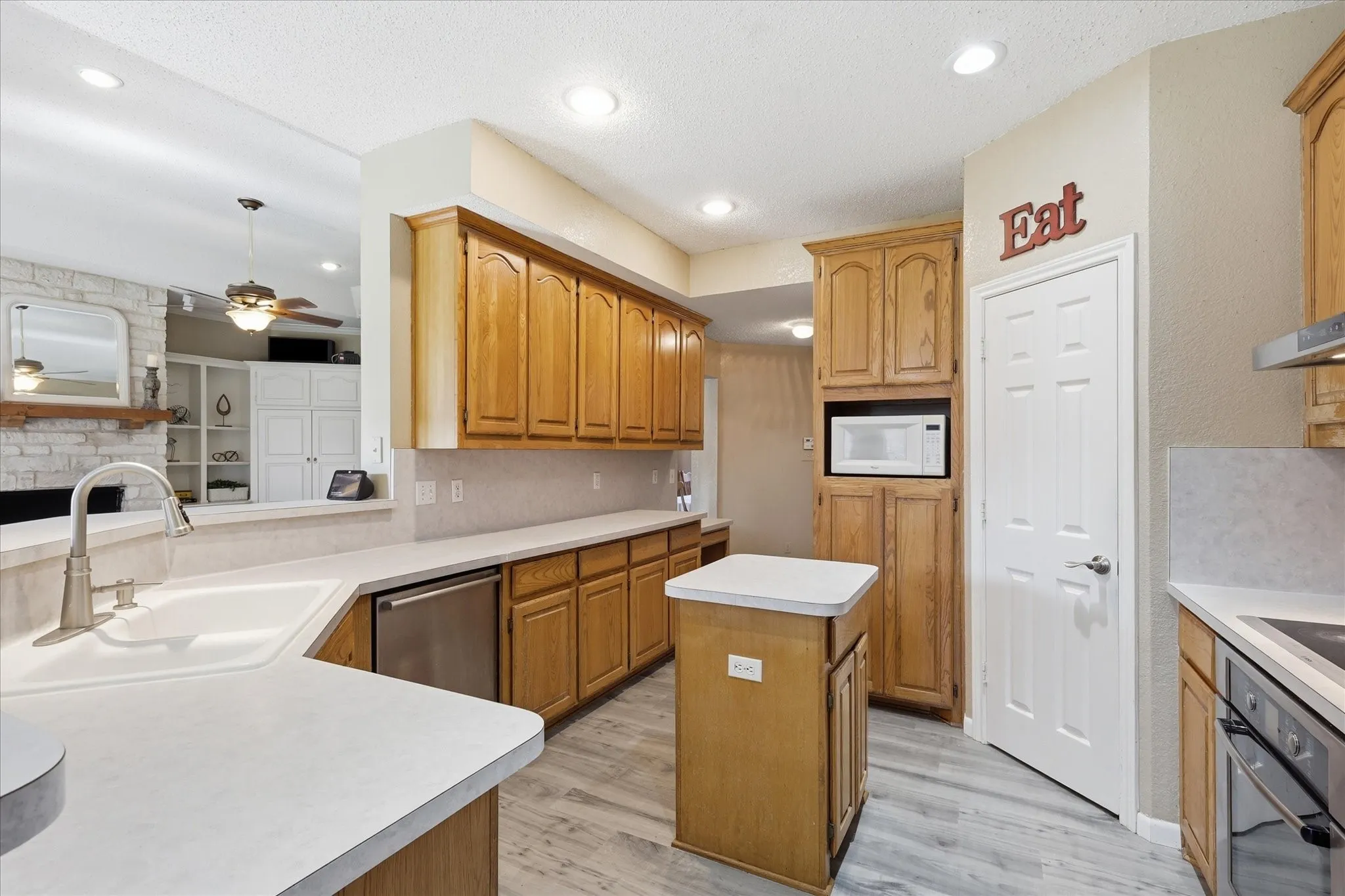 Kitchen featuring wood-finish cabinetry, solid surface countertops, a built-in microwave, and wood-finish flooring