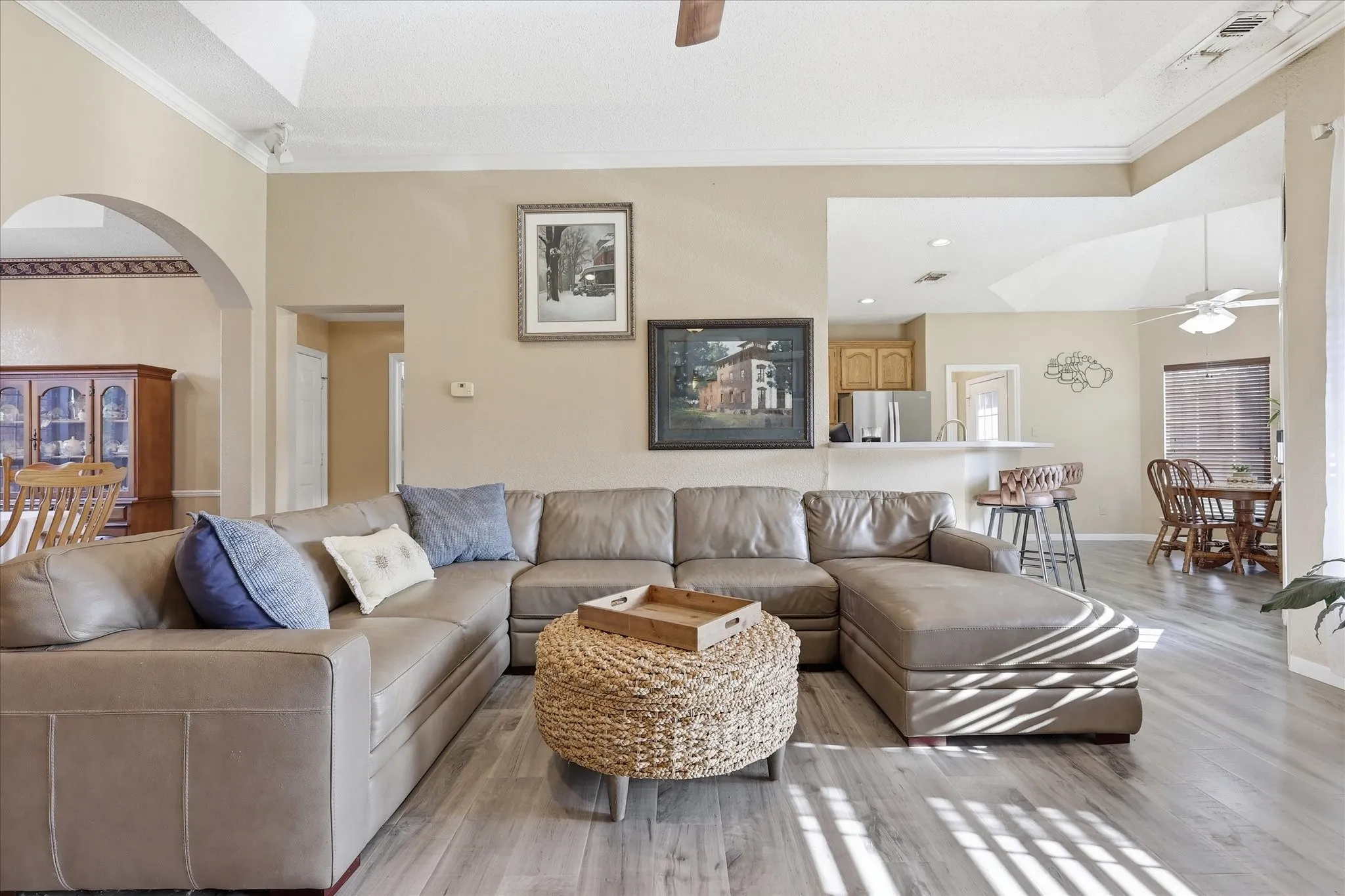 Spacious living area featuring wood-finish flooring, vaulted ceilings, and crown molding