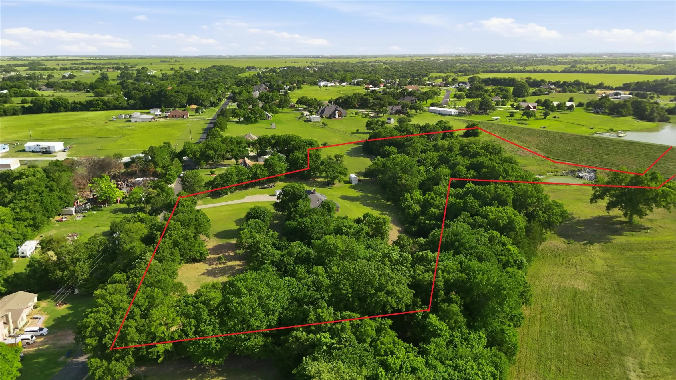 Sprawling rural estate featuring mature tree-lined grounds, open pastureland, and multiple outbuildings across expansive acreage