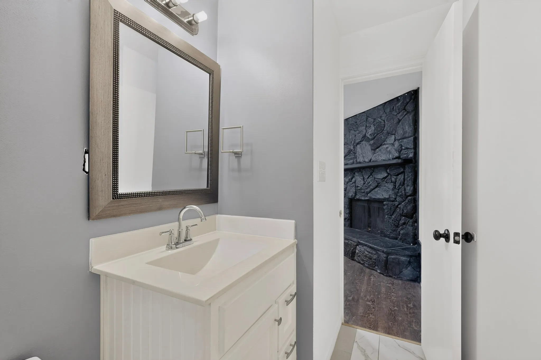 Contemporary vanity with a white countertop and integrated sink, chrome faucet, and framed mirror