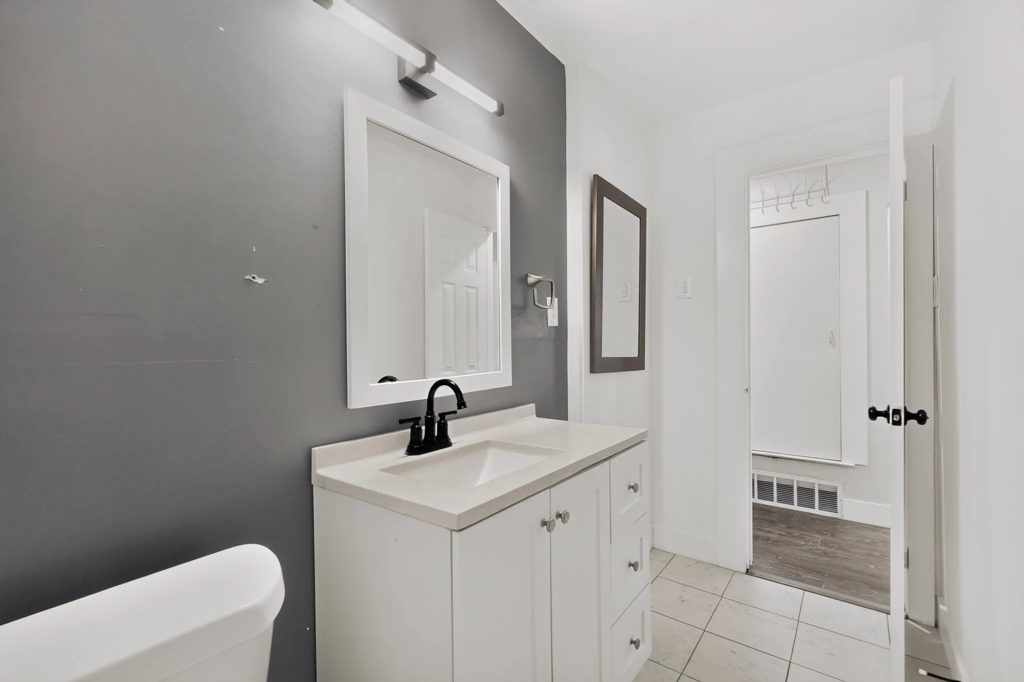 Bathroom featuring a white vanity with a light-toned countertop, a black faucet, and a framed mirror